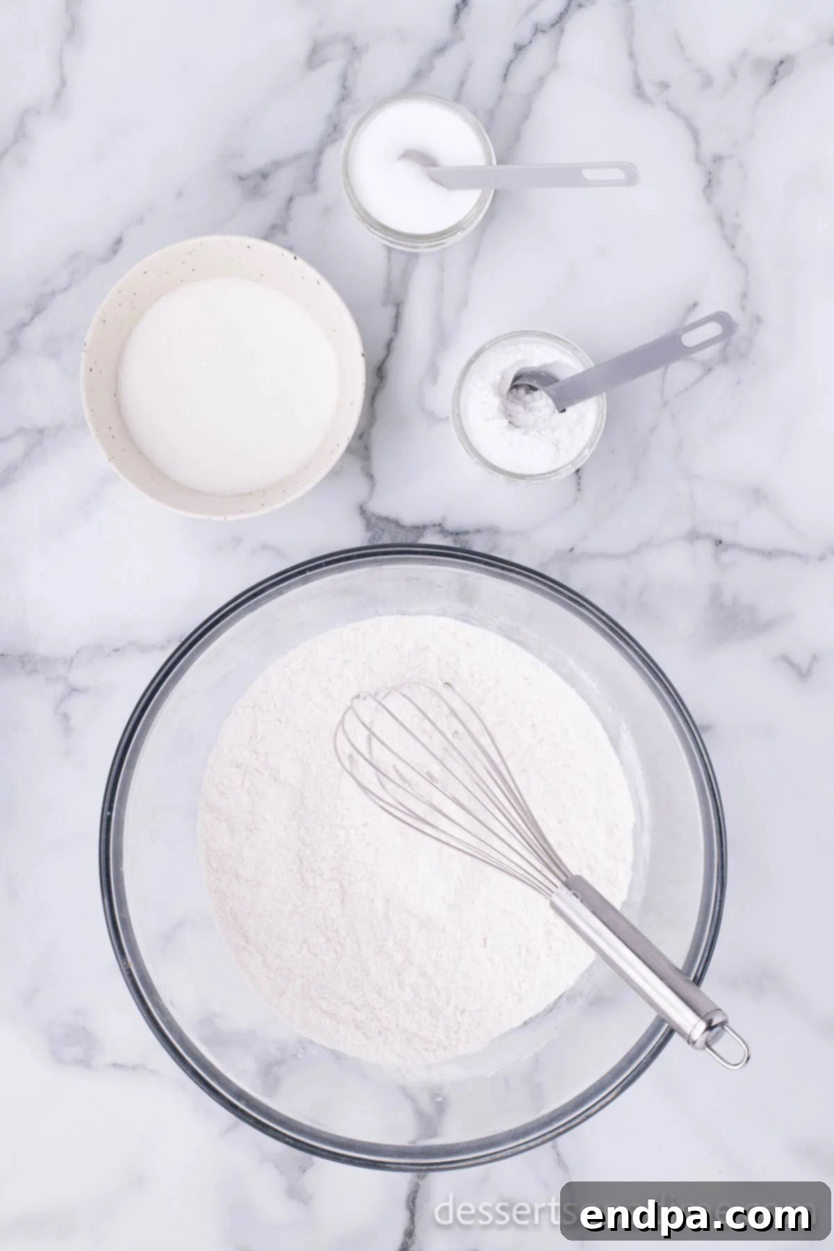 A mixing bowl containing dry ingredients: flour, sugar, baking powder, and salt, ready to be combined for the donut batter.