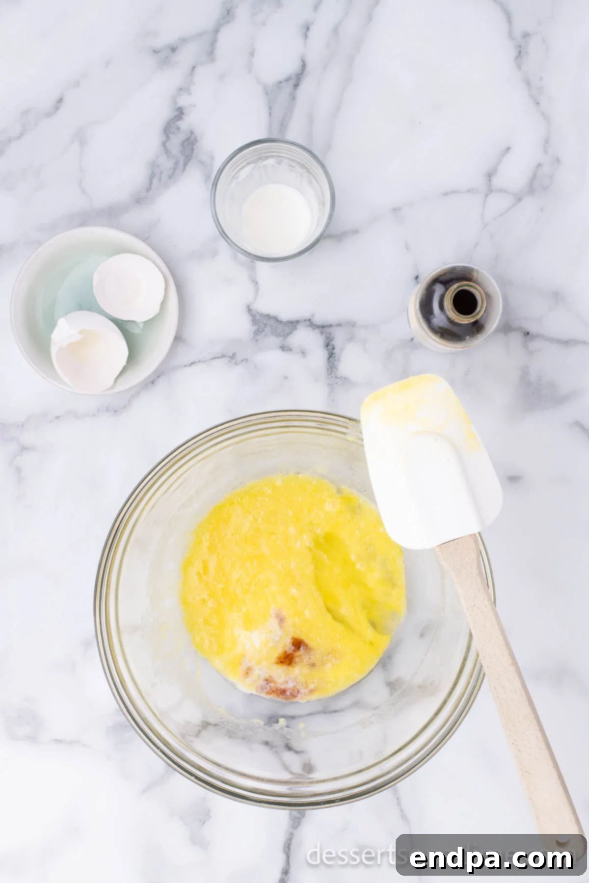 A separate bowl holding wet ingredients: melted butter, milk, egg, and vanilla extract, stirred together for the donut batter.