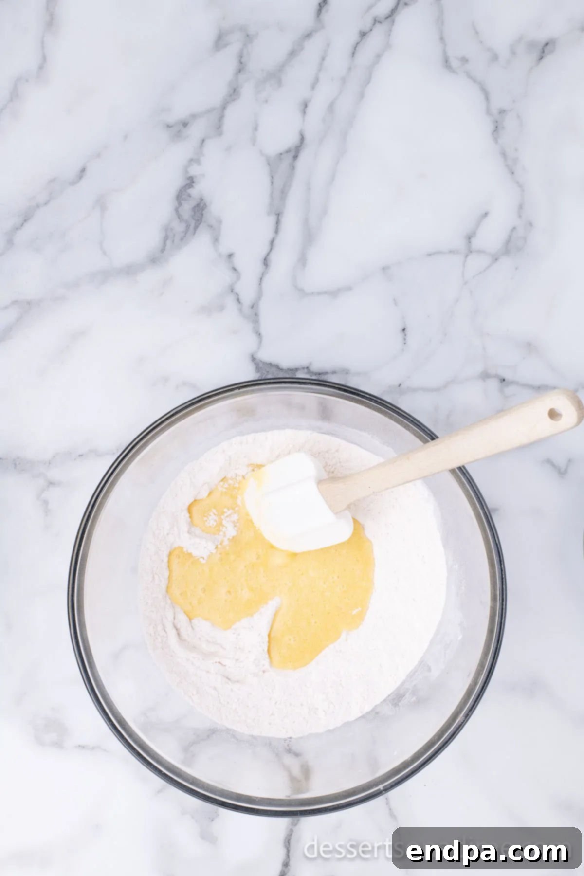 The combined wet and dry ingredients forming a smooth donut batter in a mixing bowl.