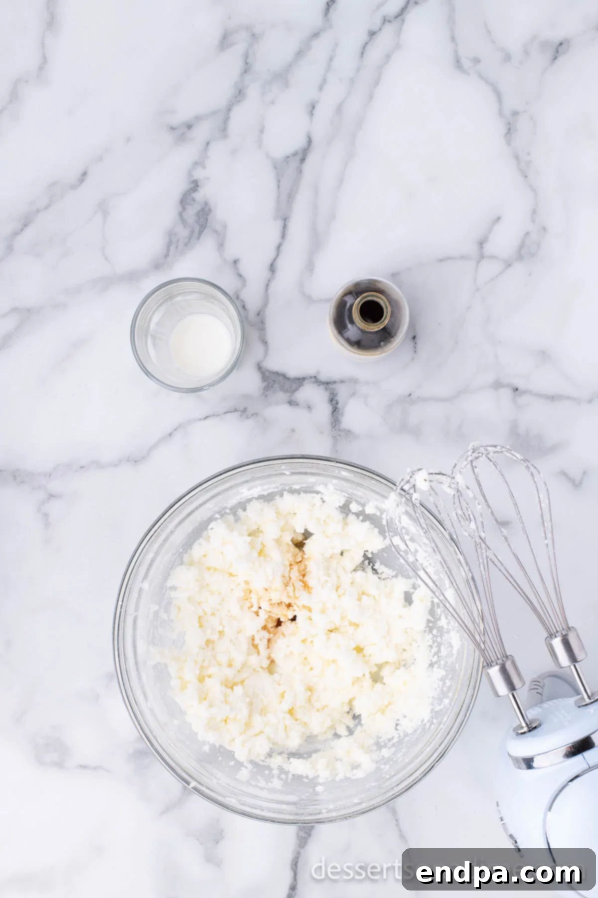 A bowl of creamy, white frosting mixture, ready for decorating the donuts.