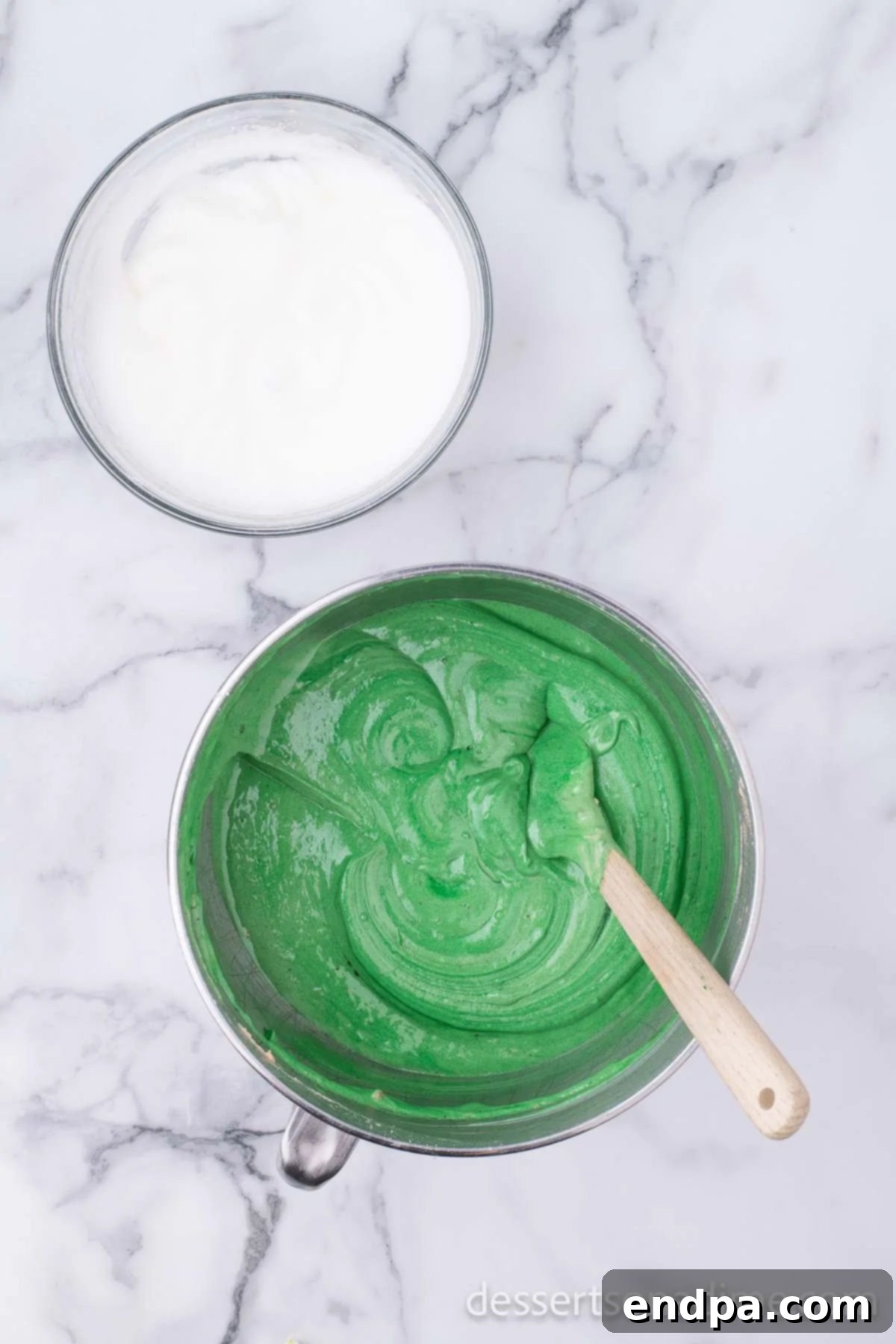 Vibrant green food coloring being mixed into cake batter.