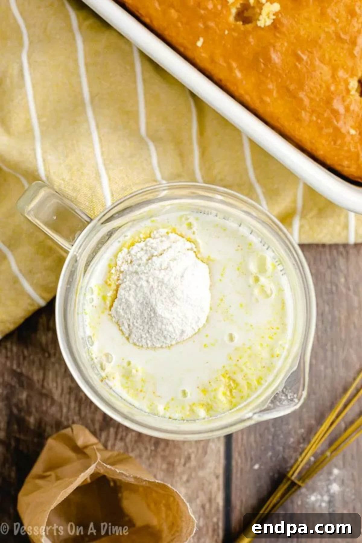 Tropical Pineapple Poke Cake 2 Vanilla instant pudding mix and milk being whisked together in a glass measuring cup.