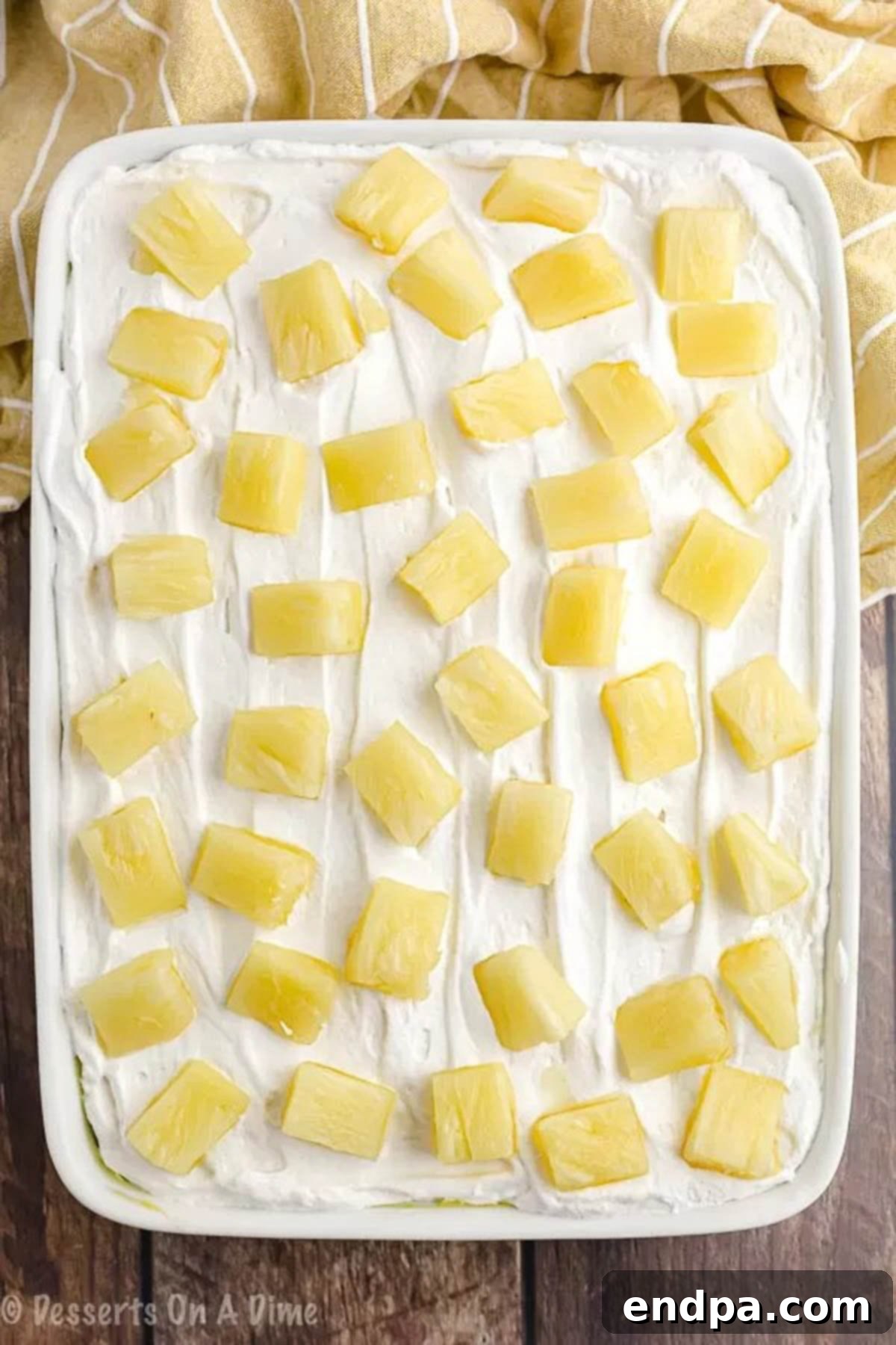 Tropical Pineapple Poke Cake 4 The pineapple poke cake fully assembled, topped with whipped topping and drained pineapple chunks.