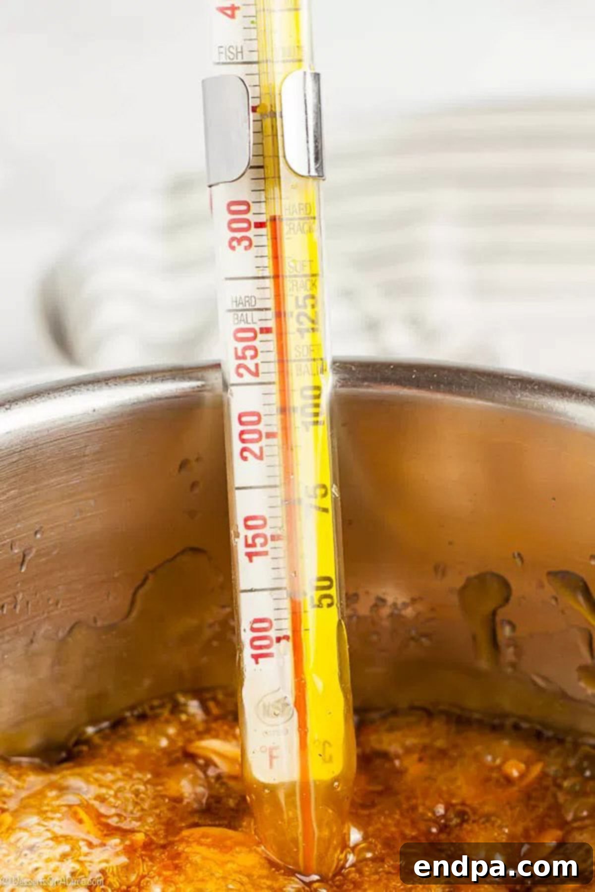 A candy thermometer accurately reads 300 degrees F, submerged in the bubbling peanut brittle mixture.