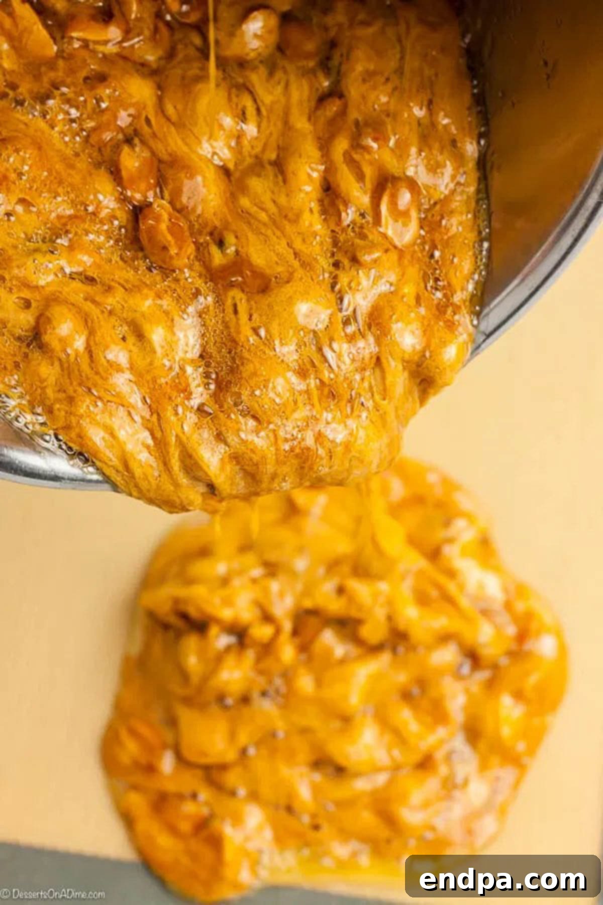 The hot, bubbly peanut brittle mixture being carefully poured and spread onto a prepared baking sheet.
