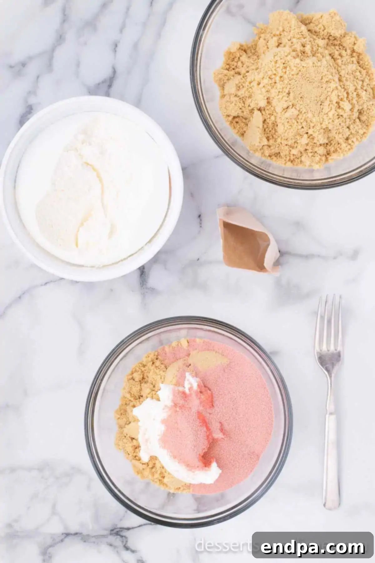 Decadent Strawberry Shortcake Cheesecake 11 Cookie crumbs mixed with whipped topping and strawberry gelatin in a bowl.