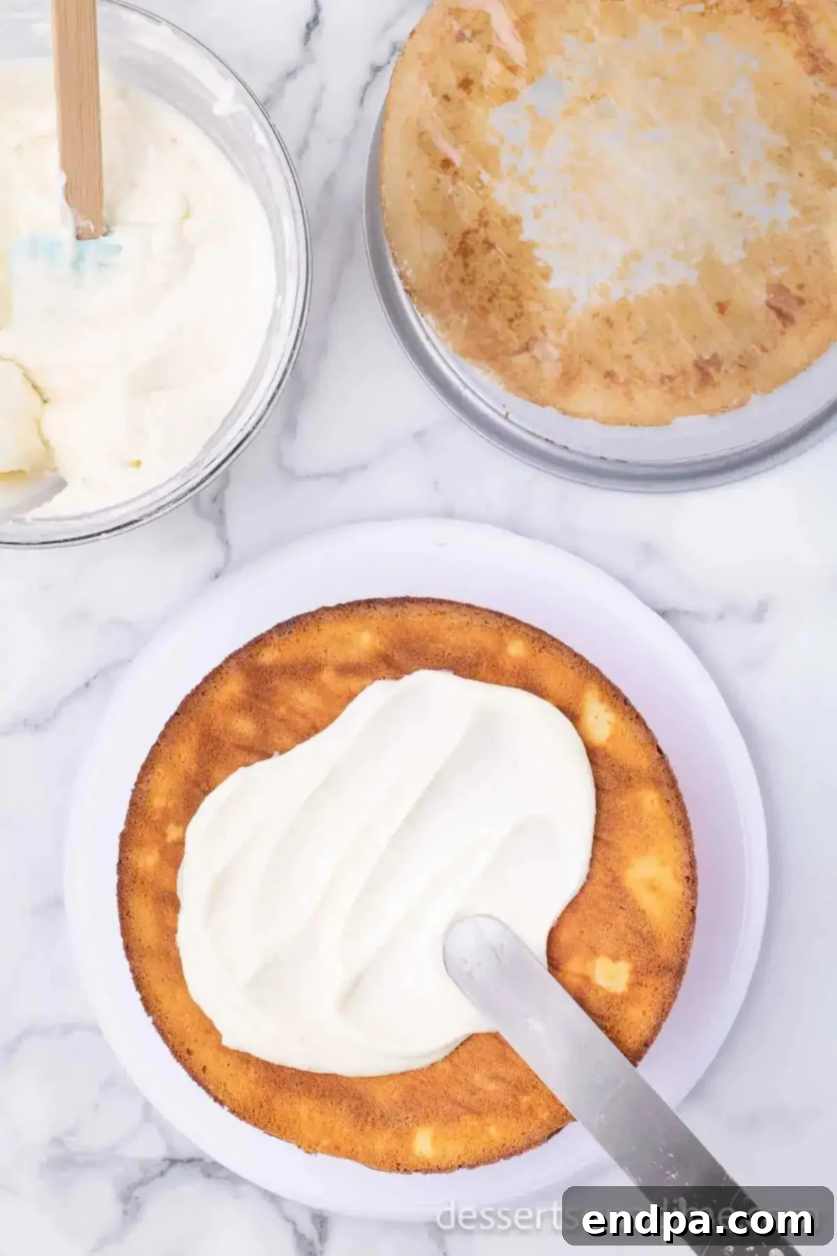 Decadent Strawberry Shortcake Cheesecake 12 A strawberry cake layer on a stand, topped with a smooth layer of cream cheese frosting.