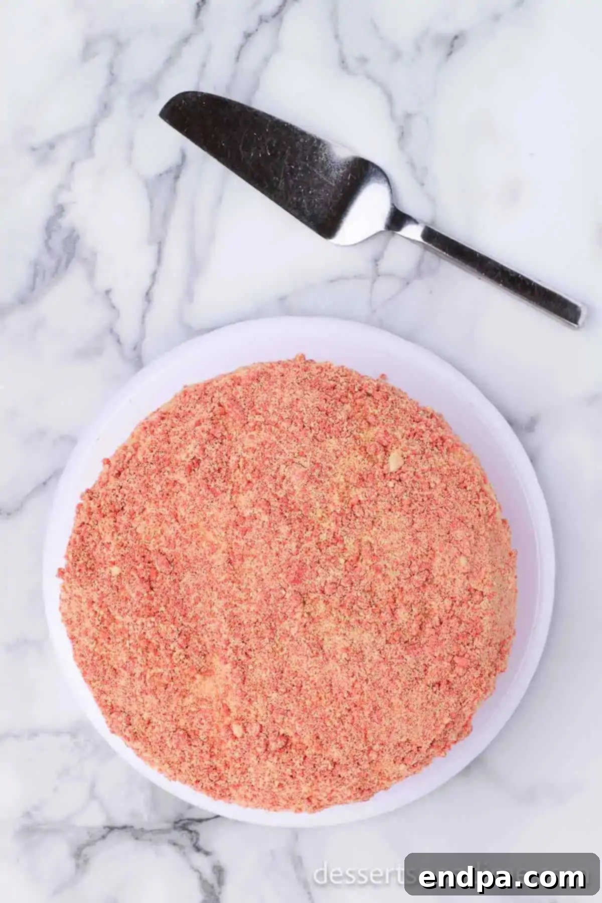 Decadent Strawberry Shortcake Cheesecake 14 The final strawberry cake layer on top, with crumb topping being pressed into the sides and top of the cake.