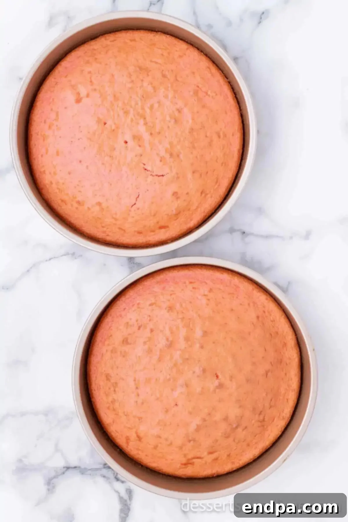 Decadent Strawberry Shortcake Cheesecake 5 Two freshly baked strawberry cakes cooling in their pans on a wire rack.