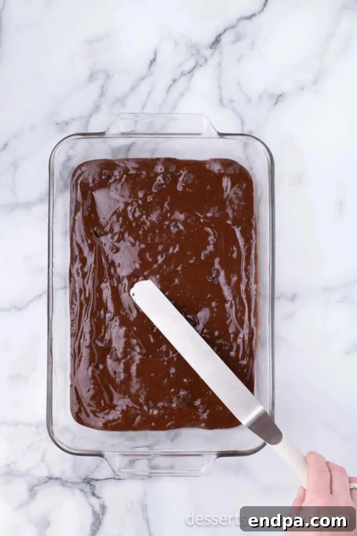Prepared brownie batter evenly spread into a 9x13 inch baking dish.