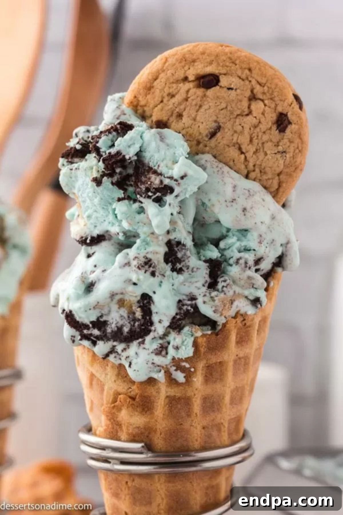 Vibrant blue Cookie Monster Ice Cream served in a crispy sugar cone, adorned with cookie crumbs.