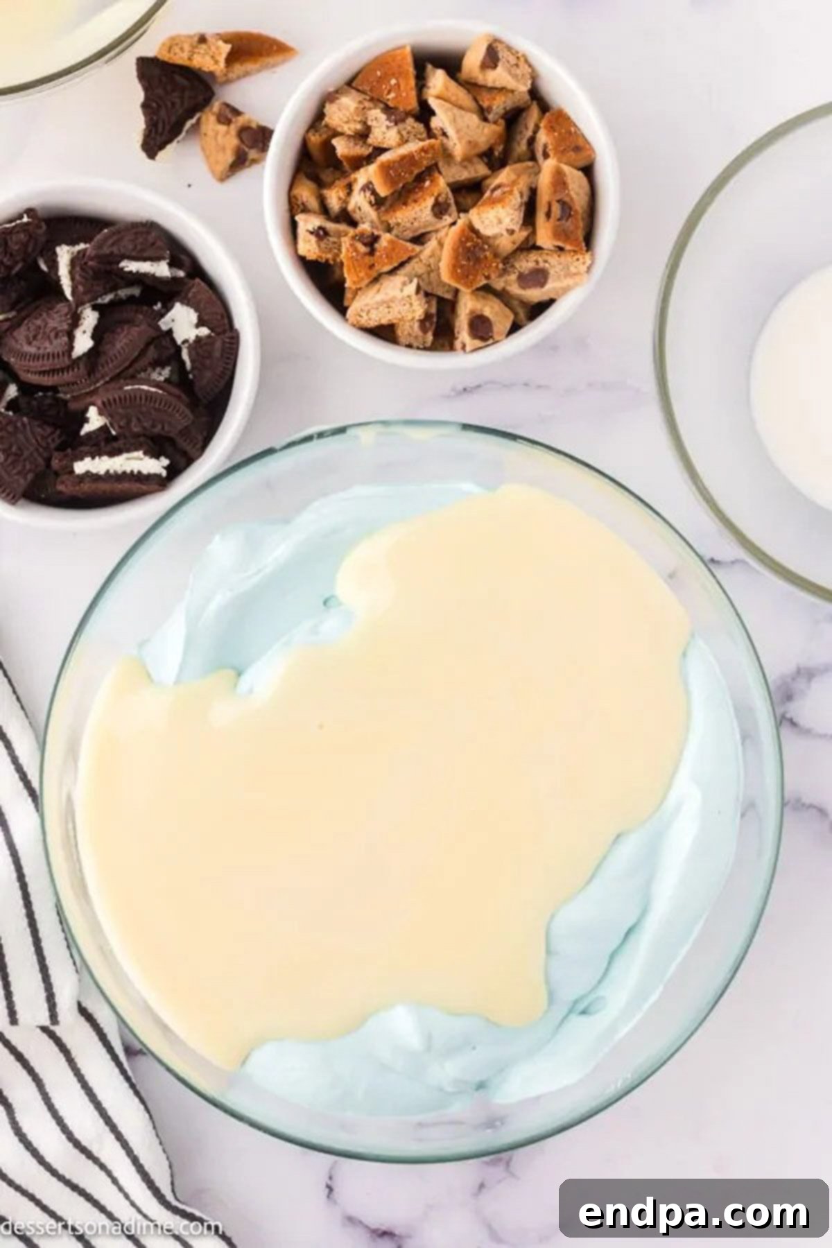 Bowl with heavy cream, vanilla, and blue food coloring being mixed.