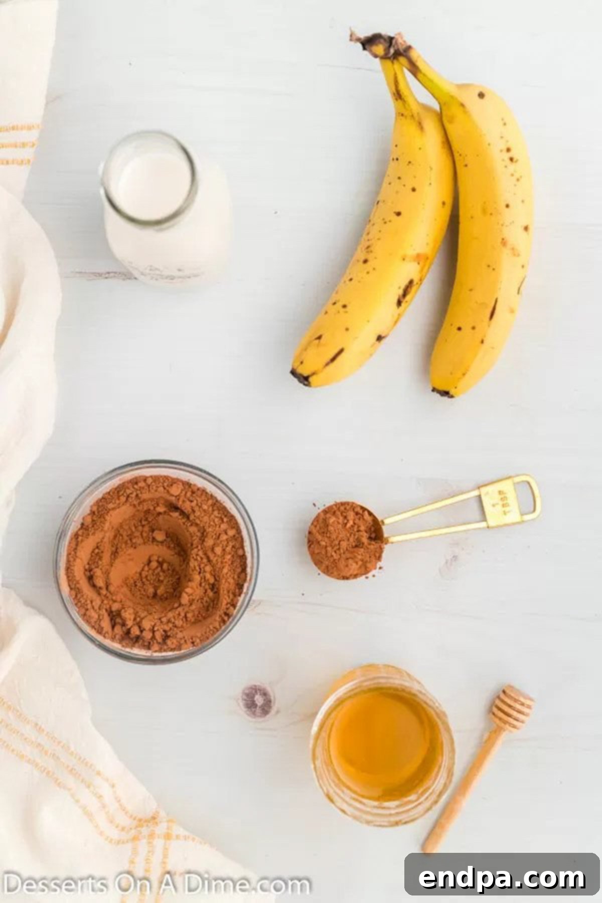 Simple ingredients laid out for chocolate banana popsicles: almond milk, ripe bananas, cocoa powder, and honey.