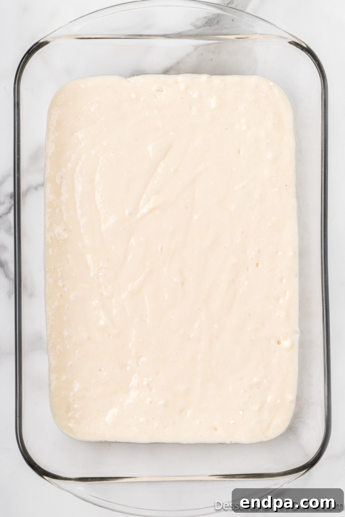 Cake batter spread evenly into a baking dish.