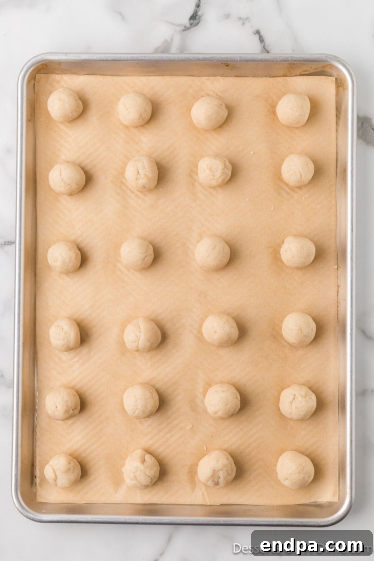 Uniform cake balls arranged on a parchment-lined baking sheet.