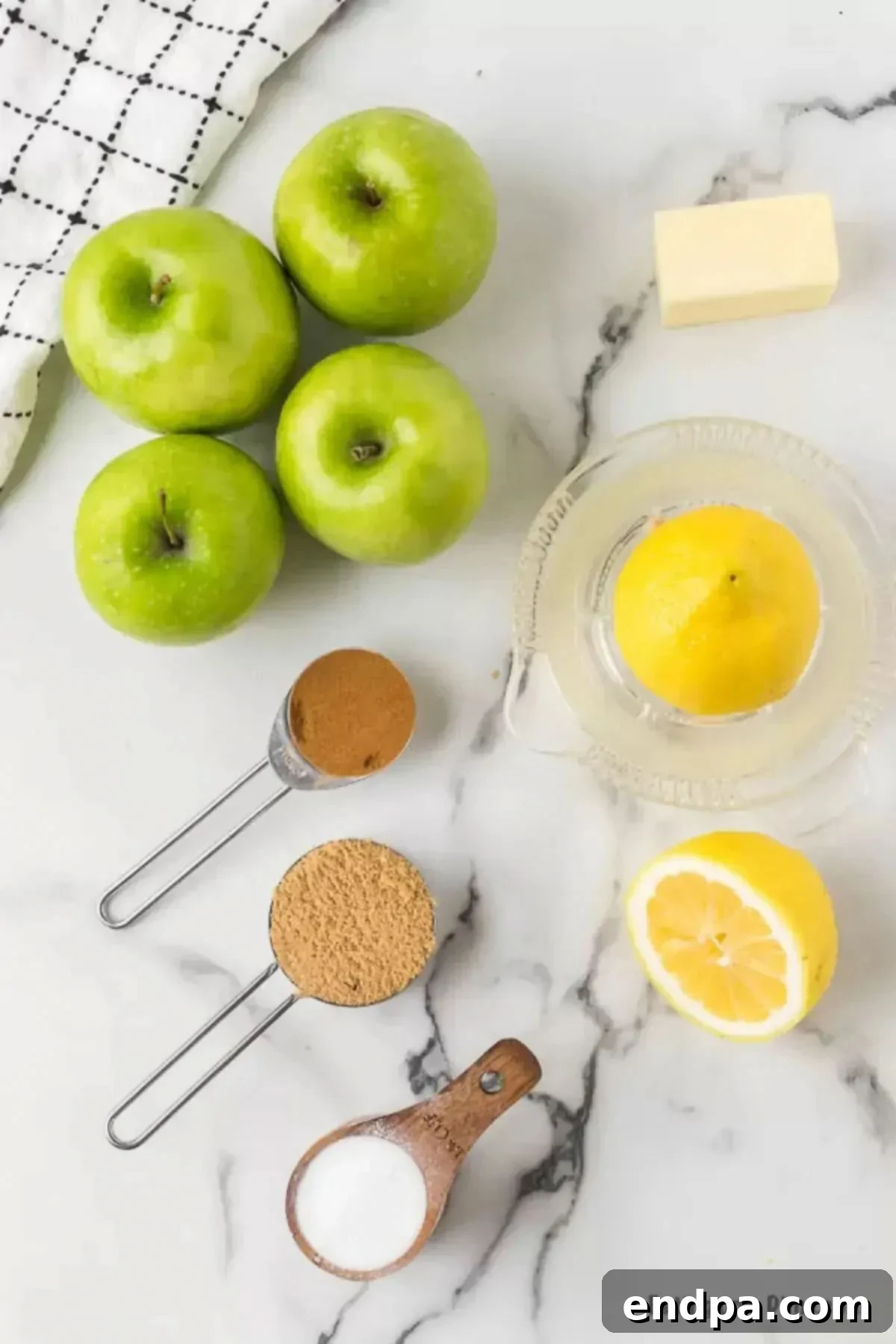 Ingredients for Fried apples including green Granny Smith apples, a fresh lemon, and brown sugar on a wooden surface.