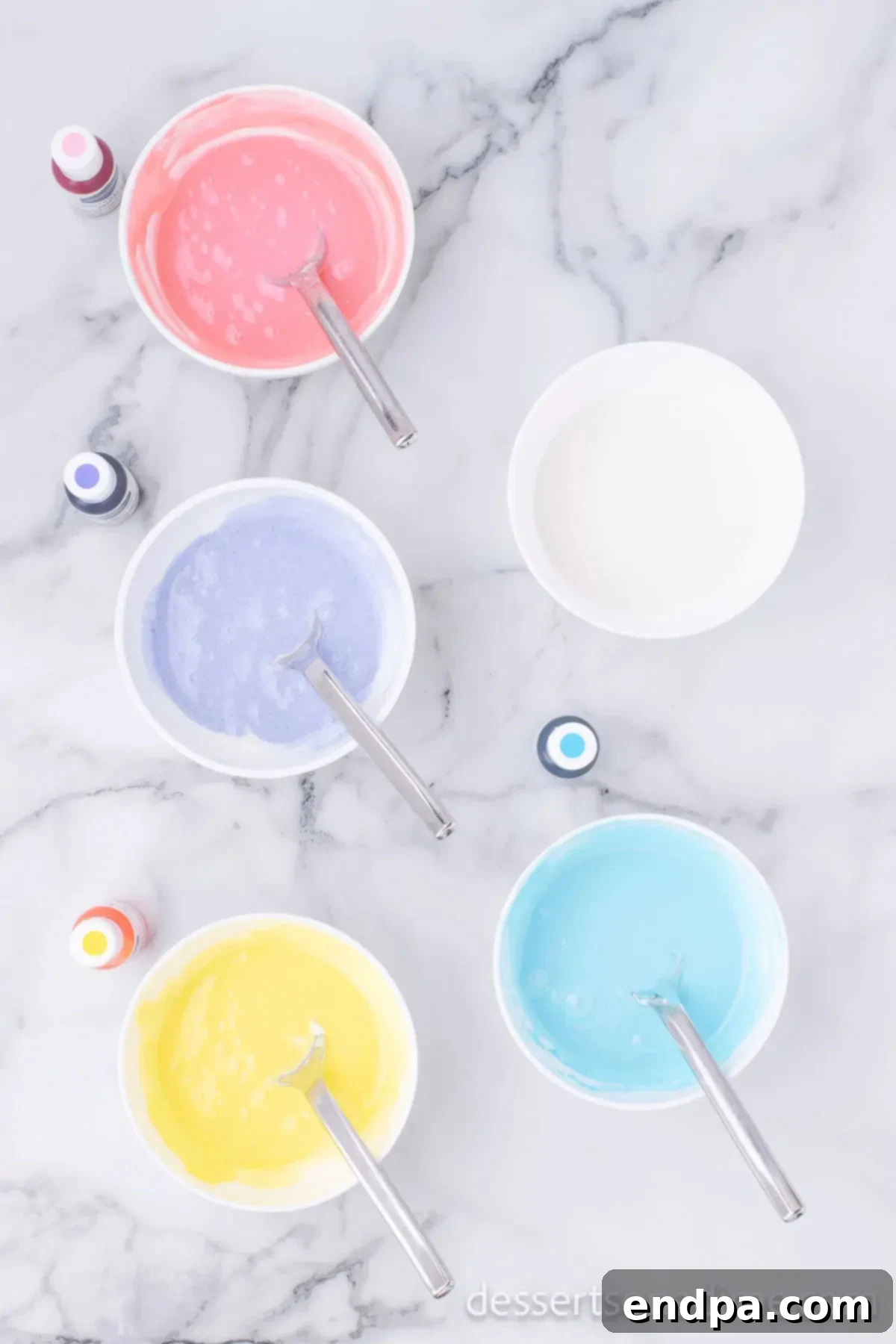 Icing in bowls with different colors of food coloring. 