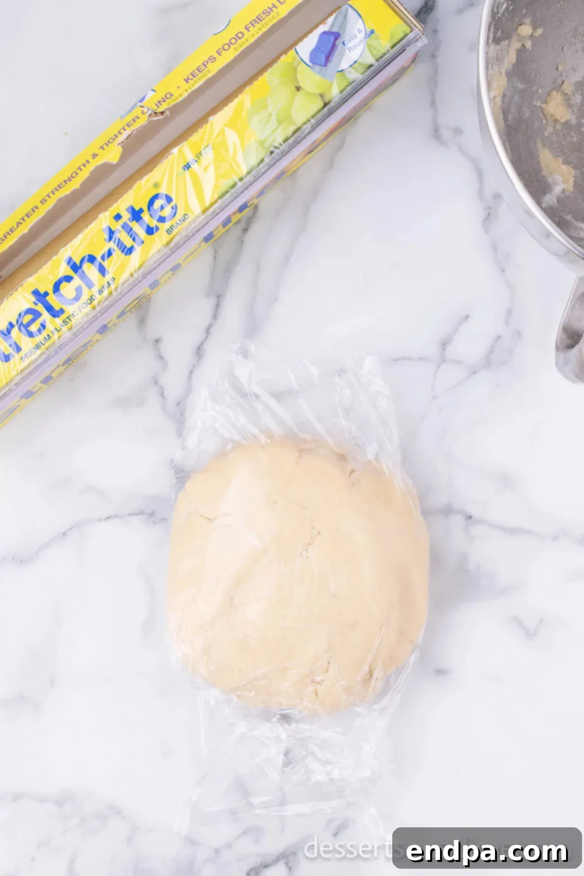 Dough in a ball wrapped in plastic wrap. 