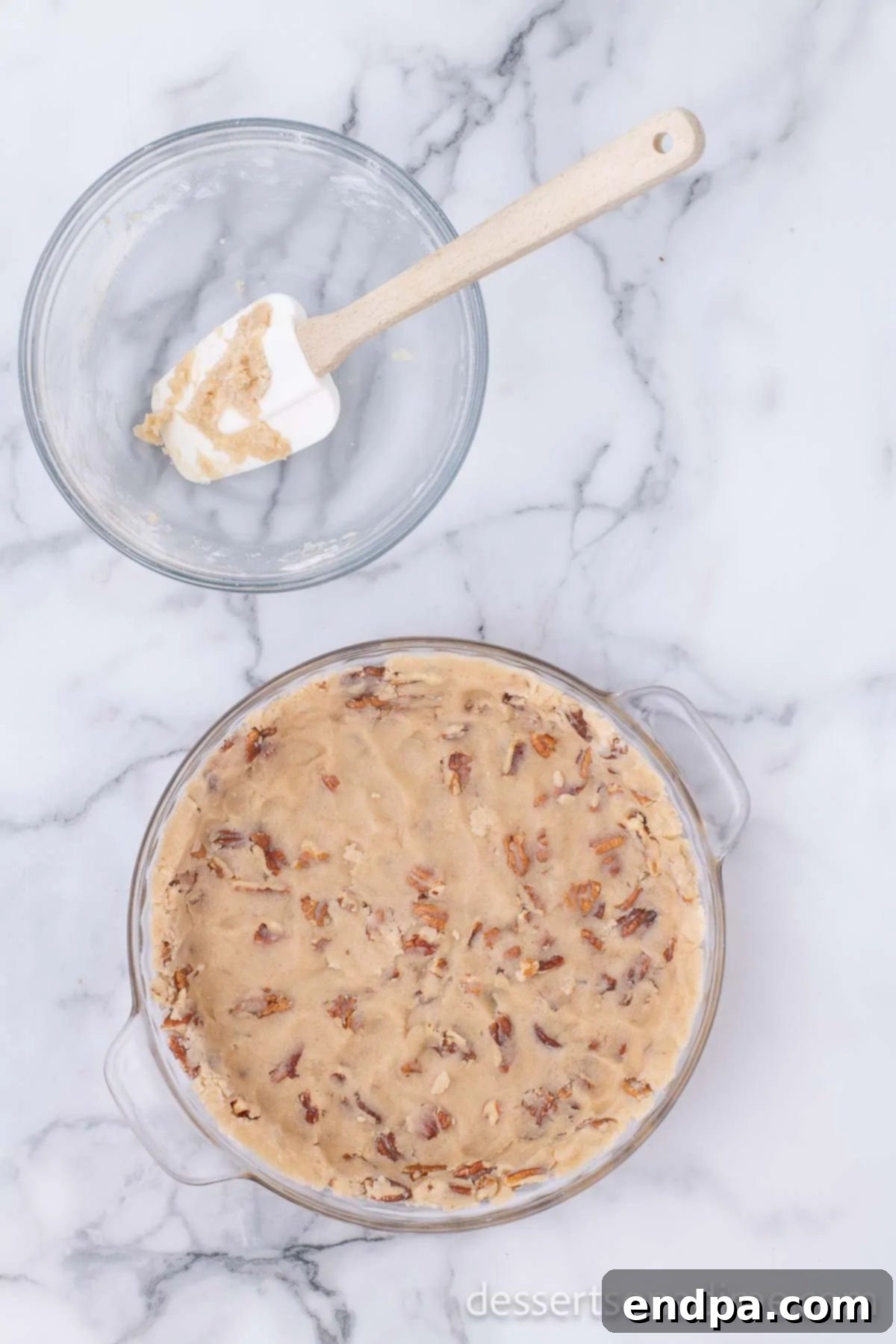 The pecan crust mixture evenly pressed into the bottom of a glass pie dish, ready for baking.