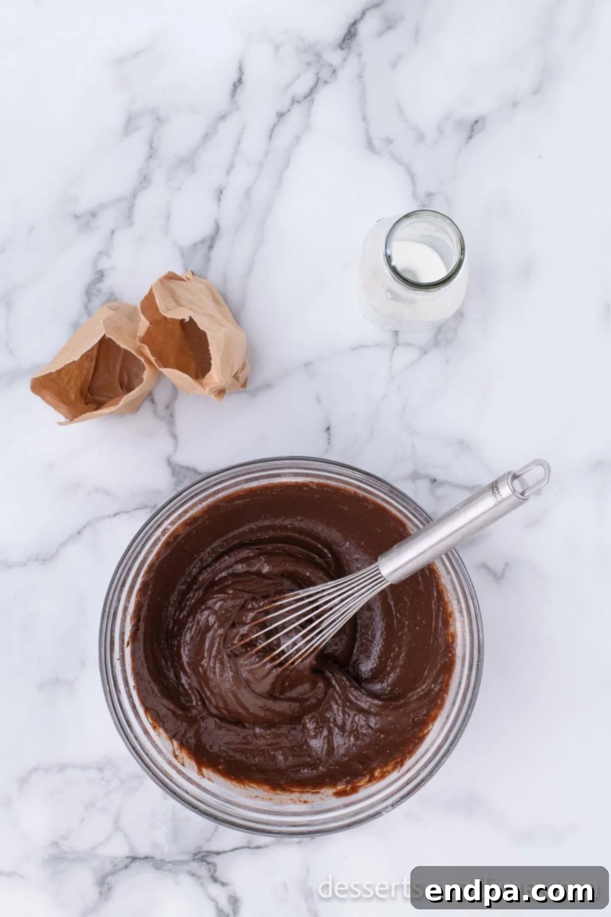 A bowl of rich, dark chocolate pudding mixture, whisked until smooth and ready to be layered.