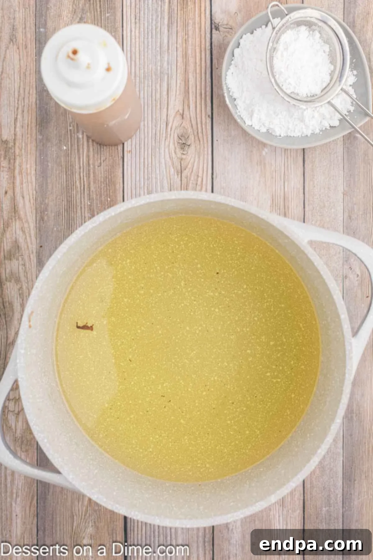 Hot vegetable oil shimmering in a deep pan, ready for frying the funnel cake batter.