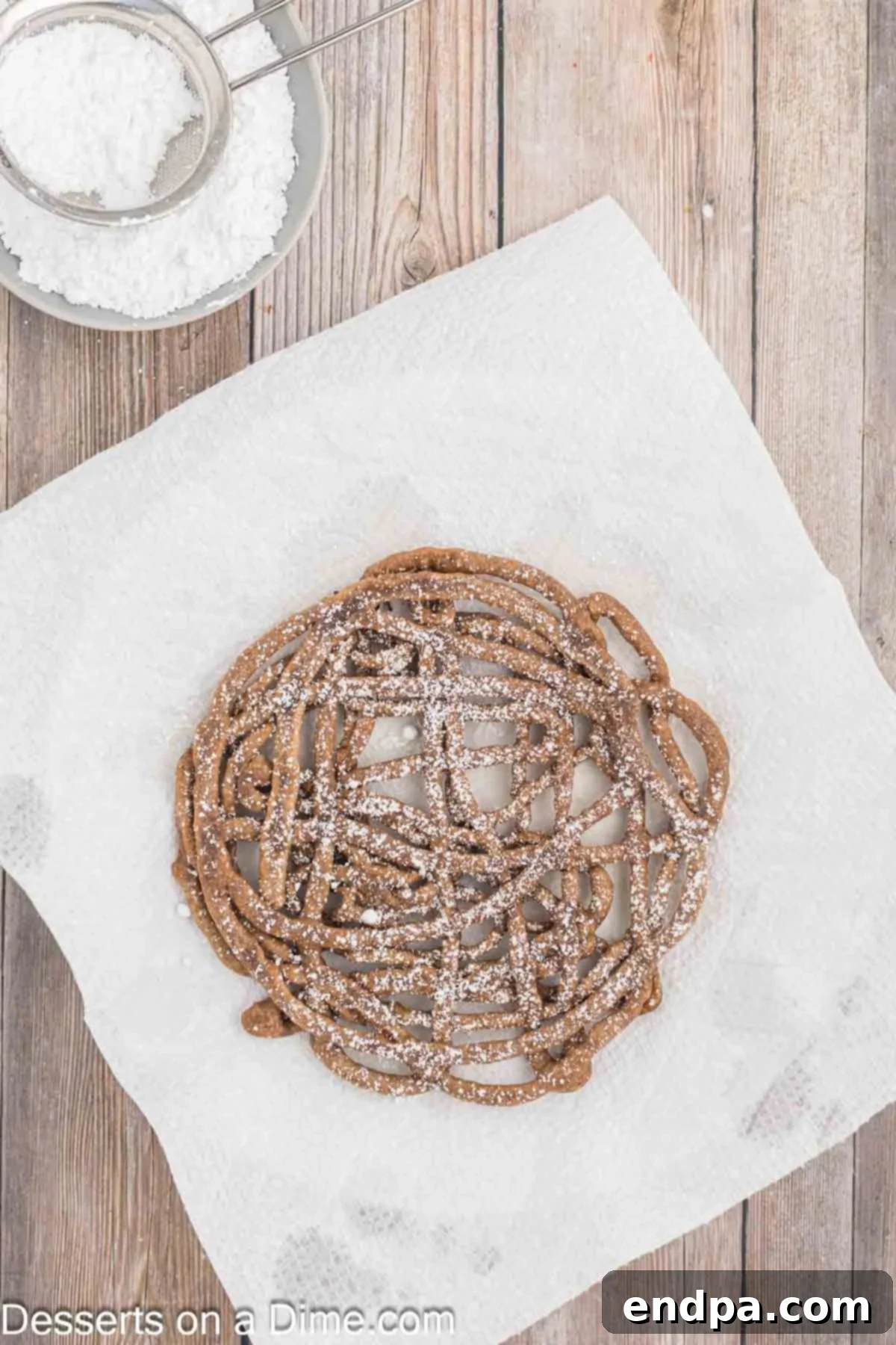A chocolate funnel cake generously topped with powdered sugar, ready to be served and enjoyed.