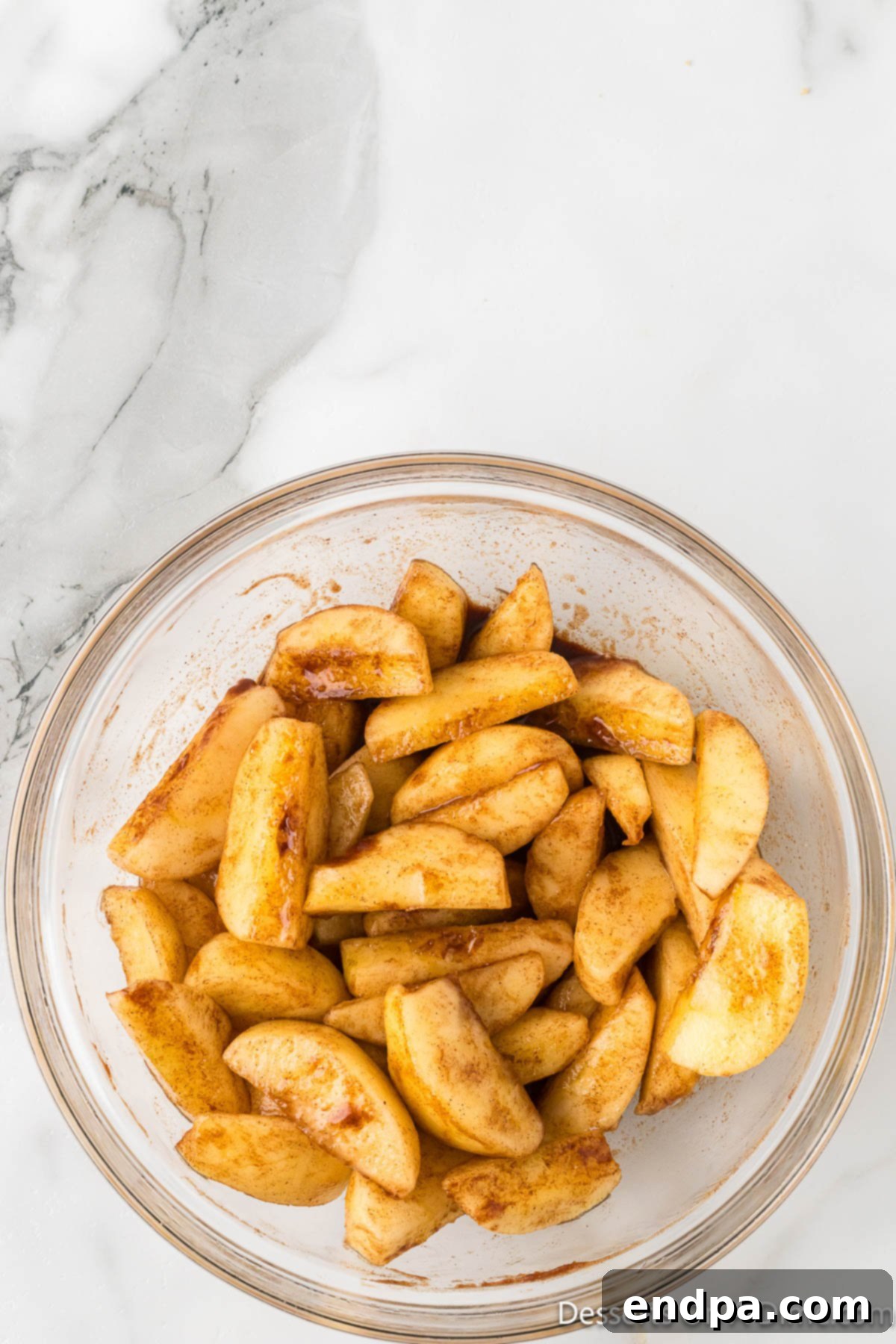 Golden Air Fryer Apple Slices 5 Sliced apples with seasoning in a bowl.