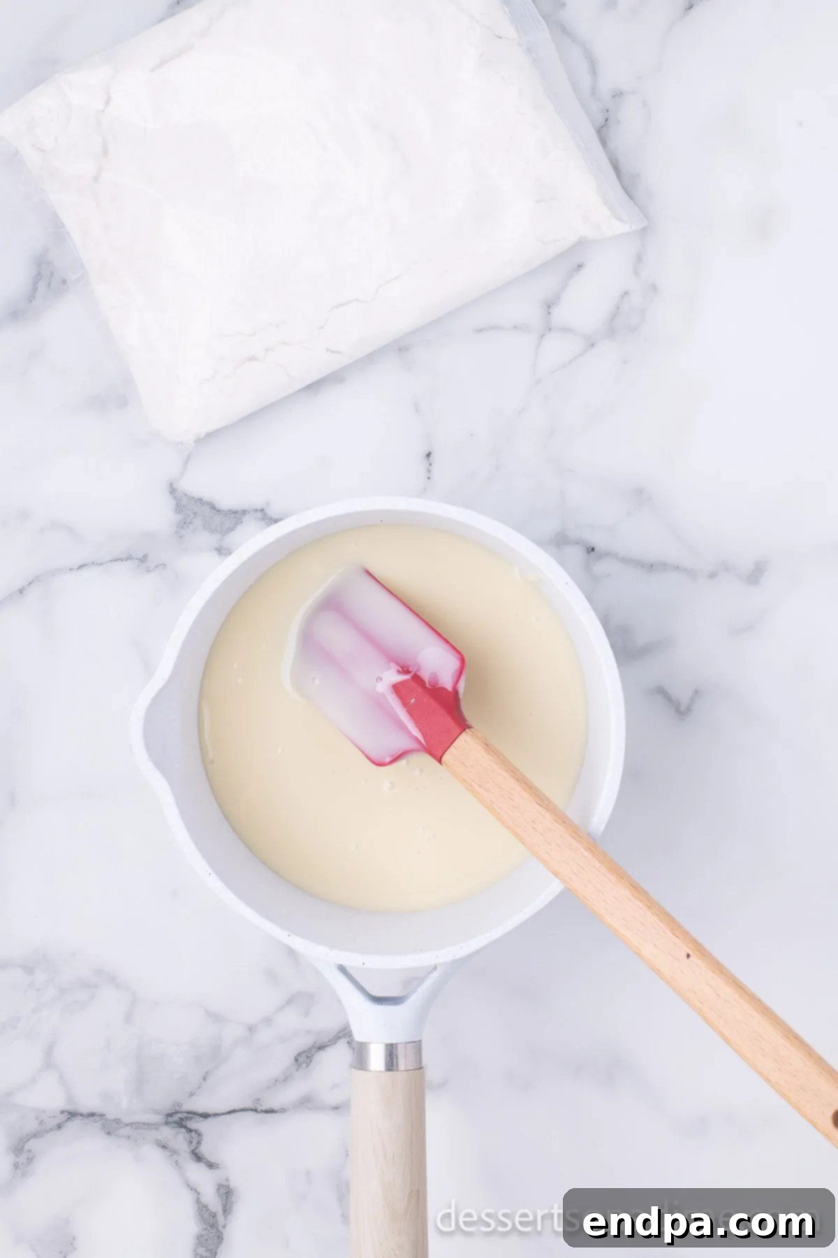 Melted mixture of sweetened condensed milk, sugar cookie mix, white chocolate chips, butter, and vanilla combined until smooth in a saucepan.