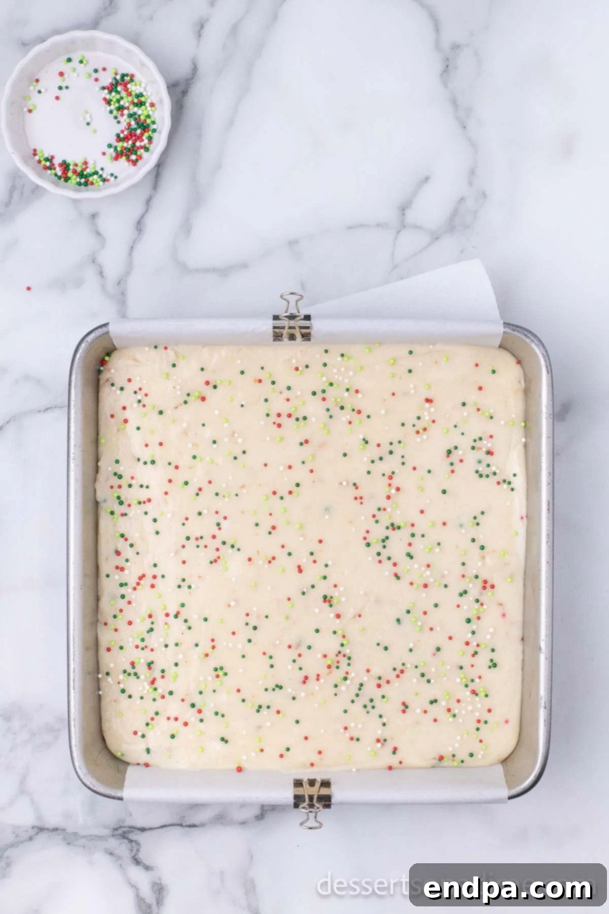 Warm Sugar Cookie Fudge mixture smoothly poured into the parchment-lined baking dish, ready for setting.