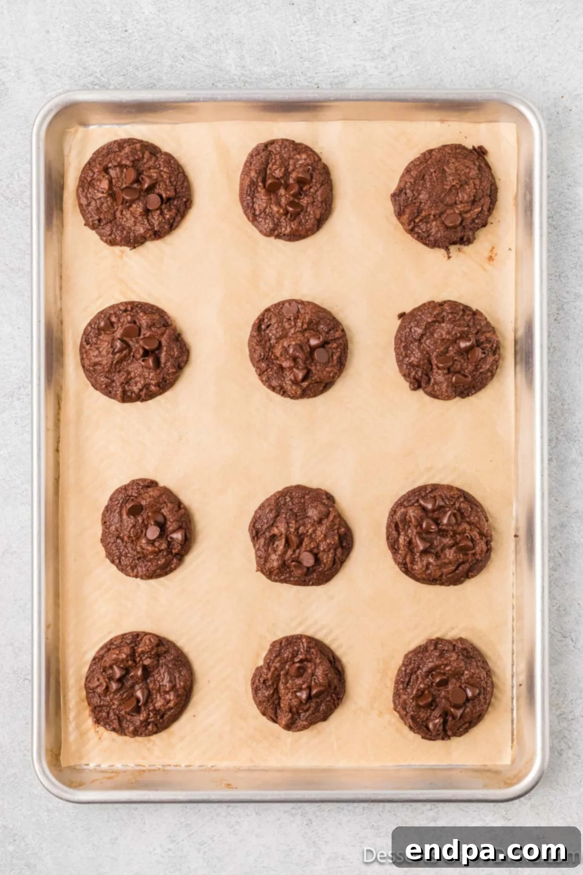 Freshly baked brownie cookies on a baking sheet, cooling slightly.