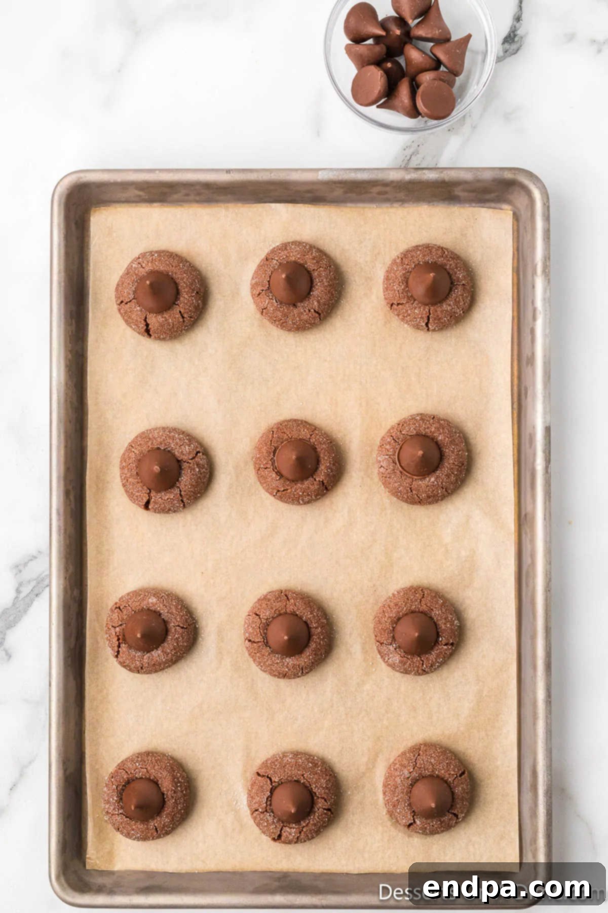 Hershey's Kisses have been placed in the center of each warm chocolate cookie, now cooling on the baking sheet.