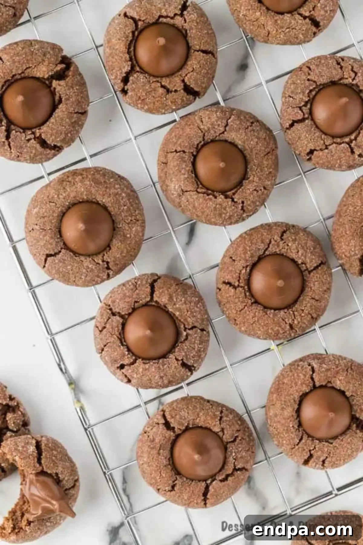 Freshly baked chocolate kiss cookies cooling on a metal wire rack.