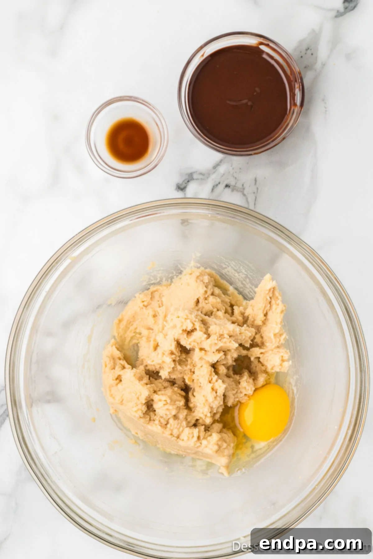 An egg has been added to the creamed butter and sugar mixture in a mixing bowl.