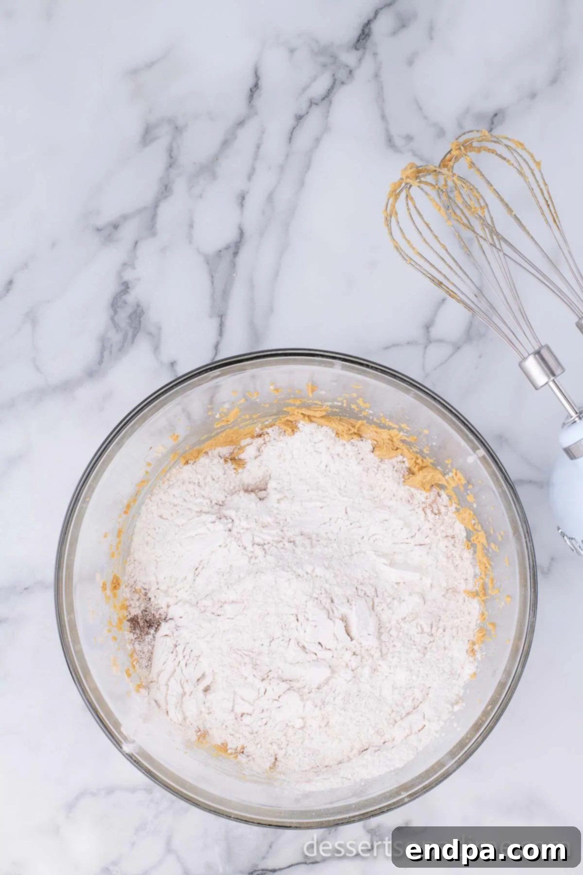 Wet ingredients and dry ingredients combined in a bowl, forming cookie dough.