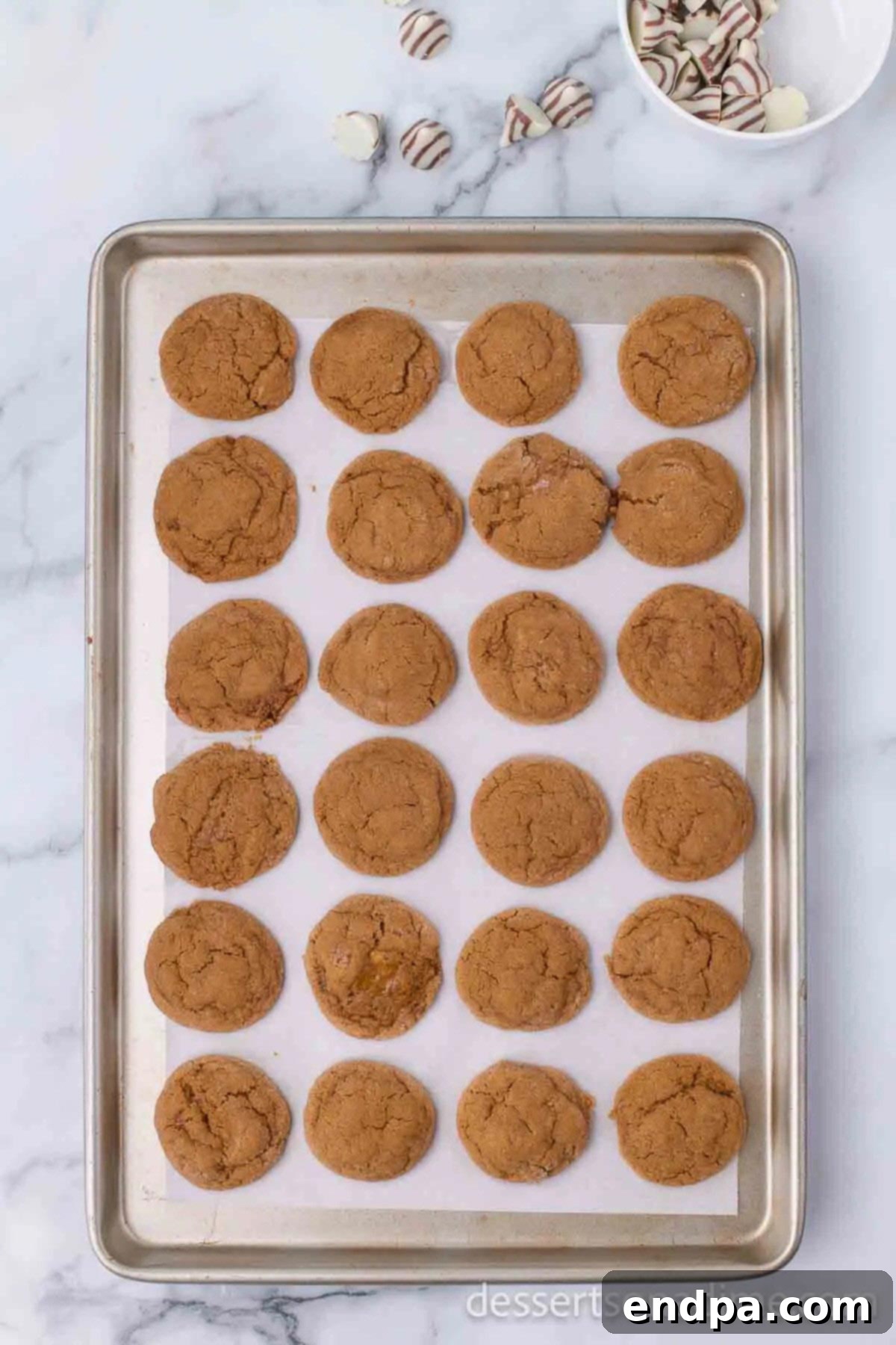 Baked gingerbread cookies on a cookie sheet, golden brown around the edges.