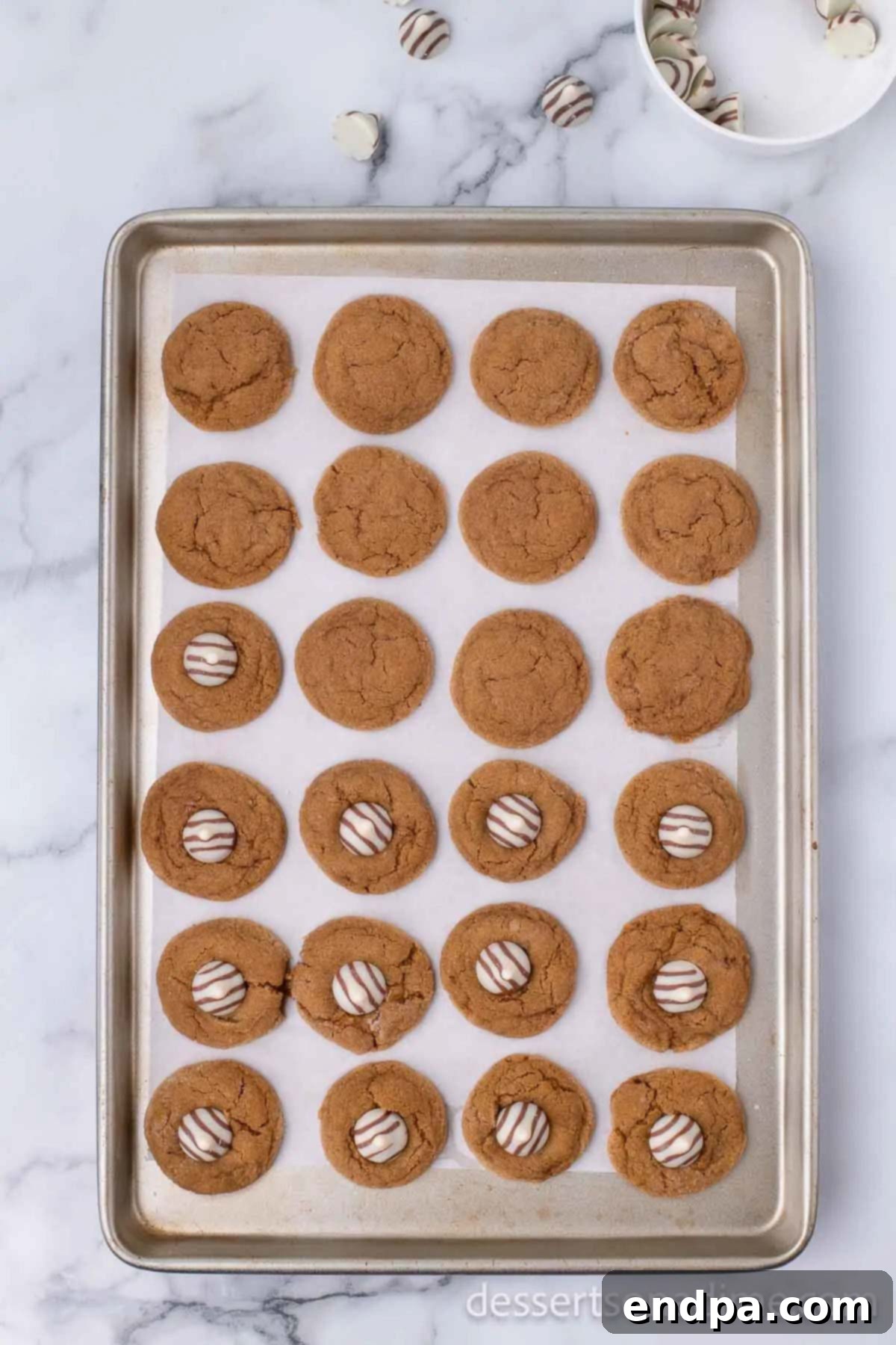 Cookie sheet with freshly baked cookies, each topped with a melting Hershey's Kiss.