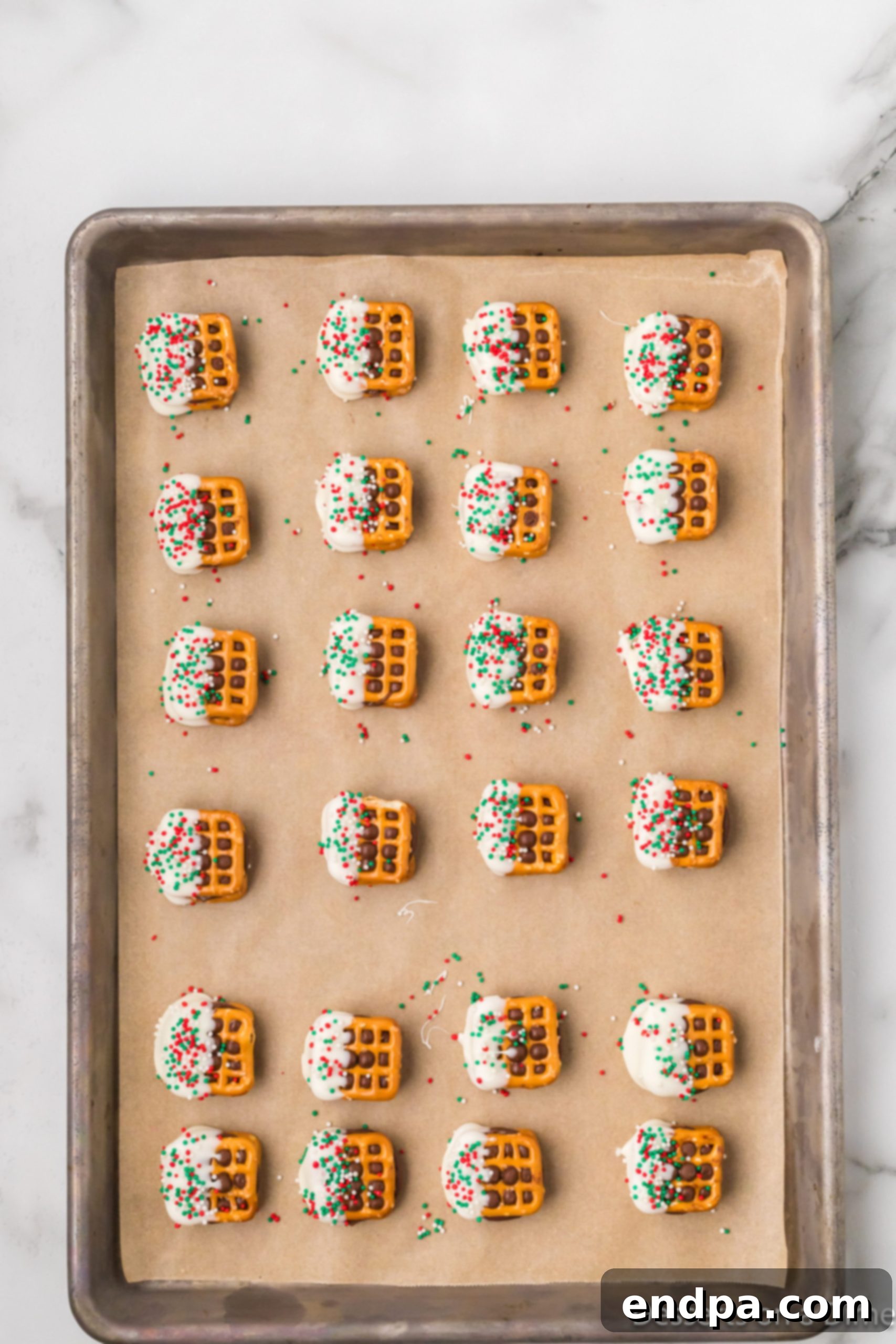 White chocolate-dipped Rolo Pretzel Sandwiches adorned with colorful sprinkles.
