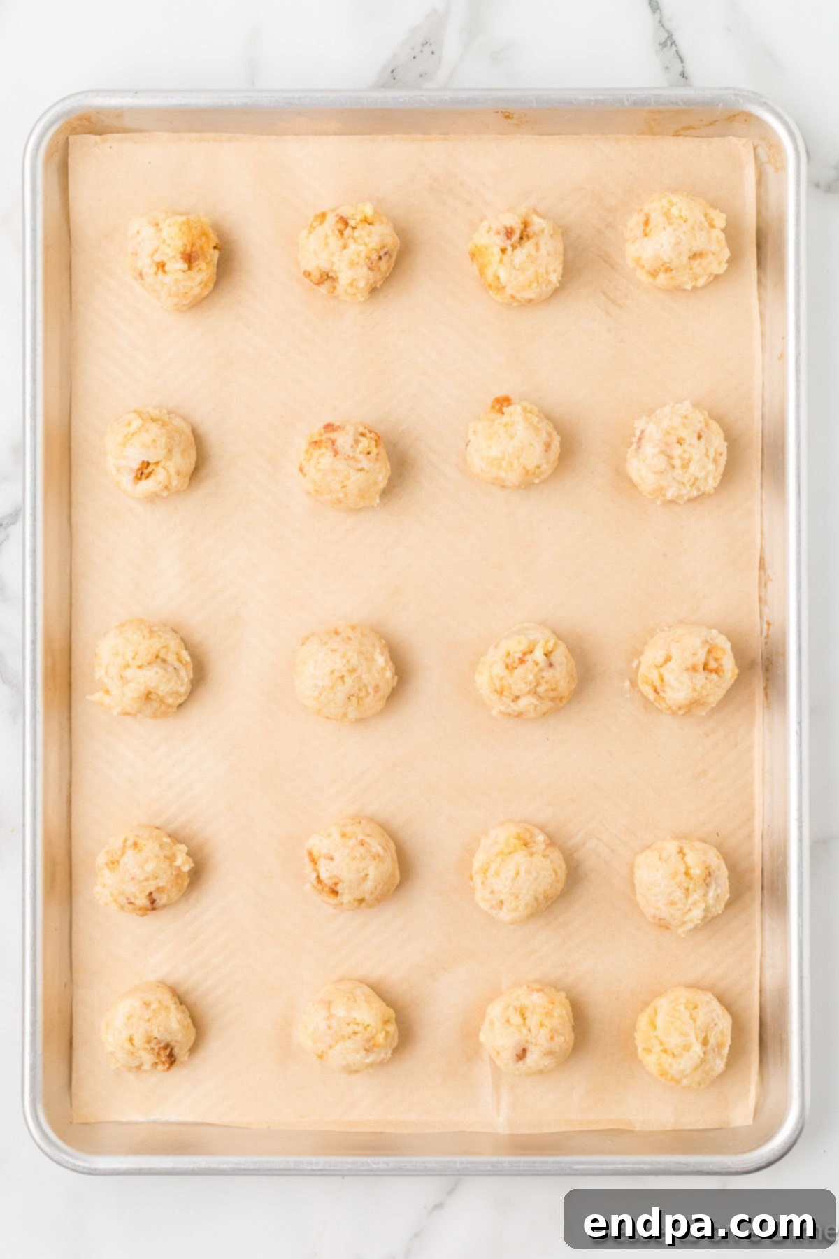 Round cake balls neatly arranged on a baking sheet, ready for chilling.