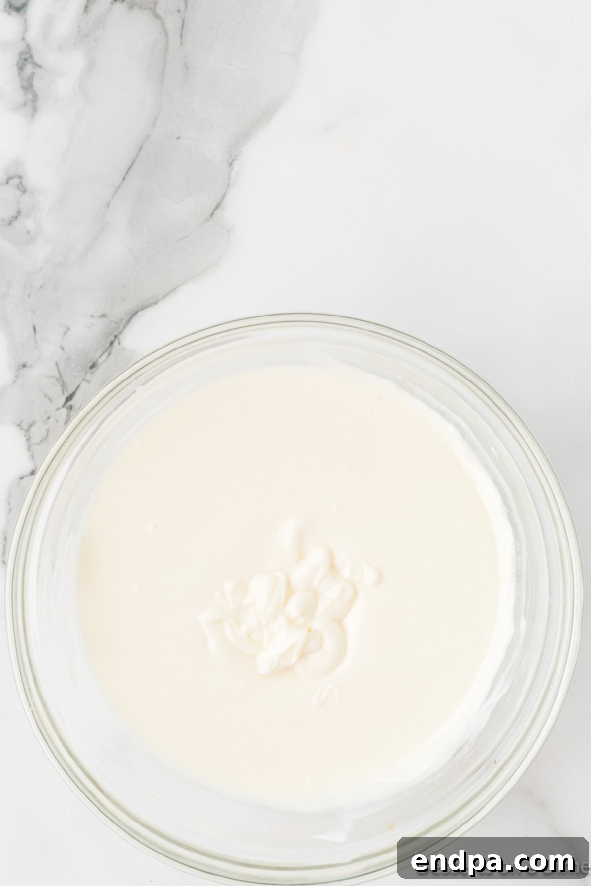 Melted white chocolate or almond bark in a glass bowl.