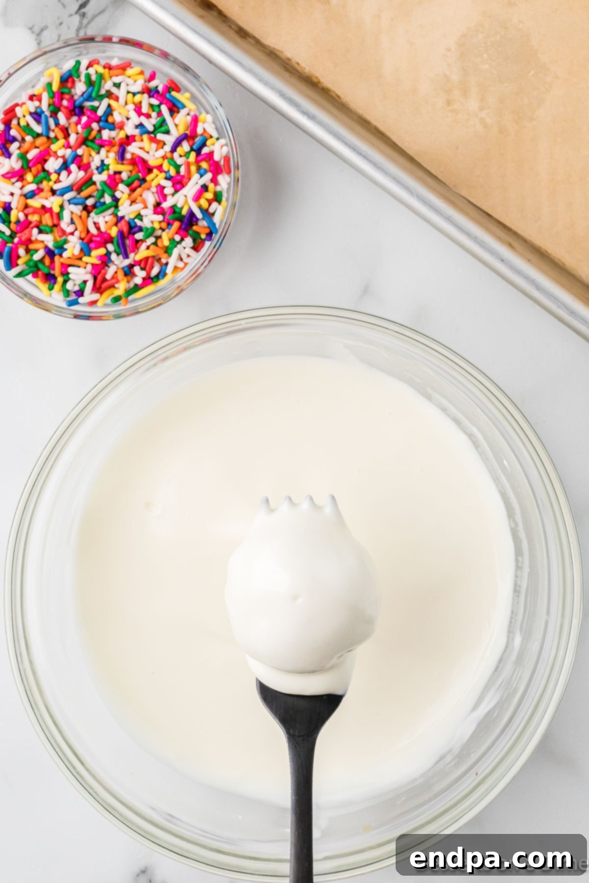 A cake ball being dipped into melted chocolate with a fork.