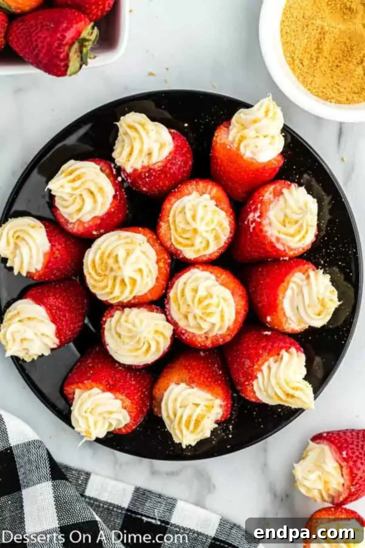 A stunning platter of finished cheesecake stuffed strawberries, garnished with graham cracker crumbs, ready for serving.