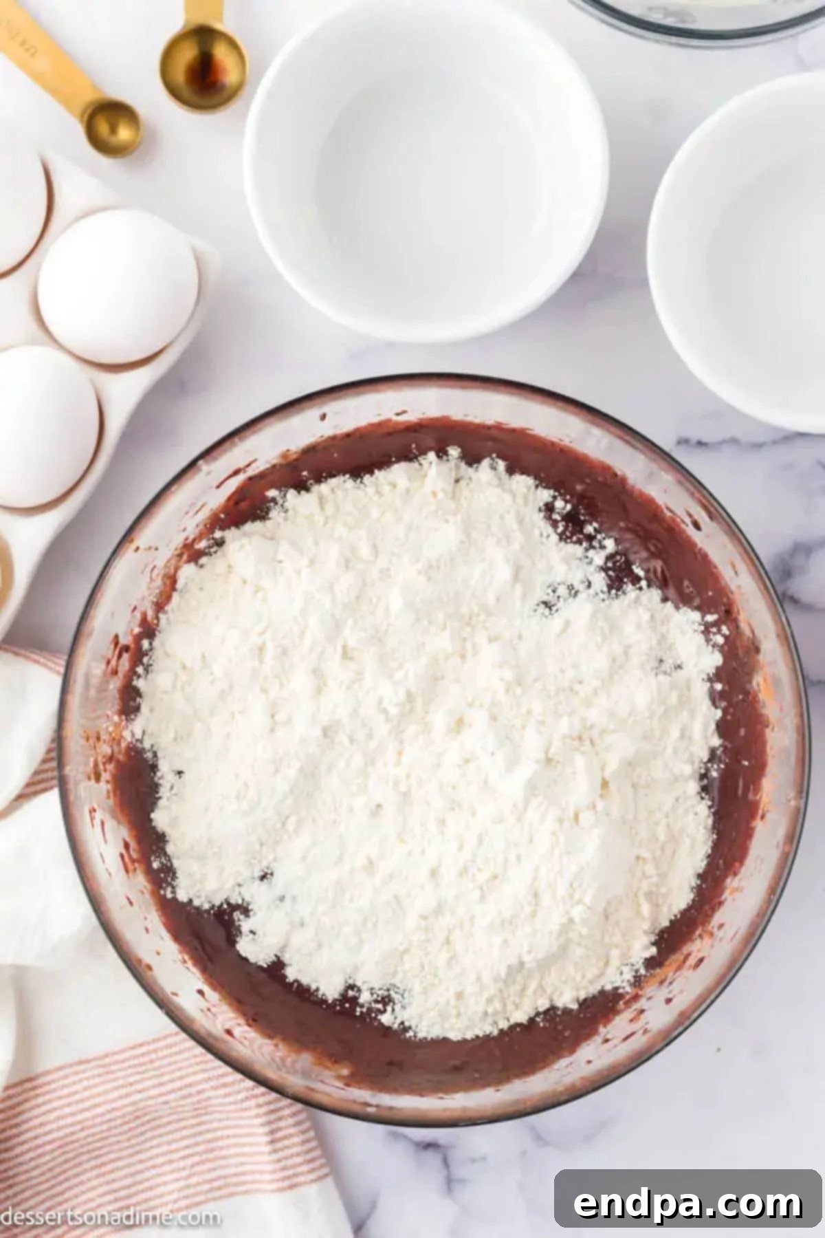 Swirled Red Velvet Cheesecake Brownies 5 Wet and dry ingredients for the red velvet brownie batter are added to a bowl and combined.