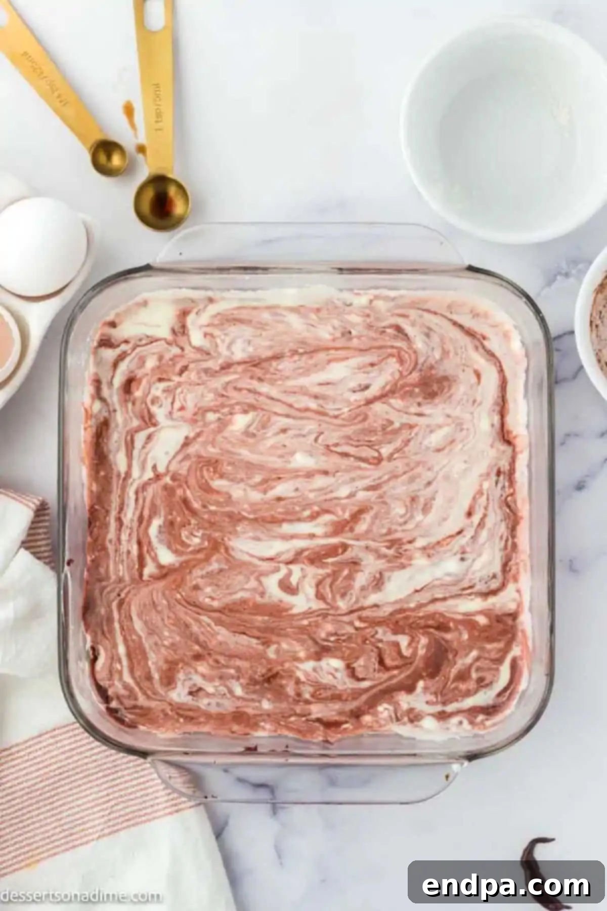 Swirled Red Velvet Cheesecake Brownies 7 Brownie and cheesecake batter swirled together in a baking dish, creating a marble pattern.