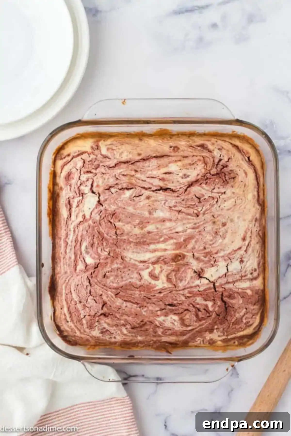 Swirled Red Velvet Cheesecake Brownies 8 Brownies baked and cooling in the pan, showing a golden top and rich red edges.