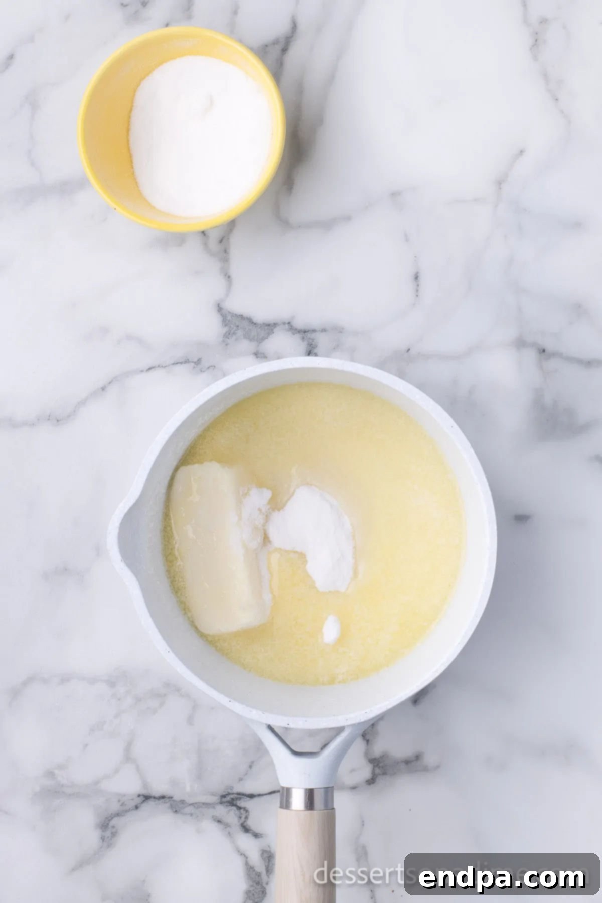 Unforgettable Craving Cake 6 Image showing the white wine glaze ingredients being heated and whisked in a small saucepan on the stovetop.