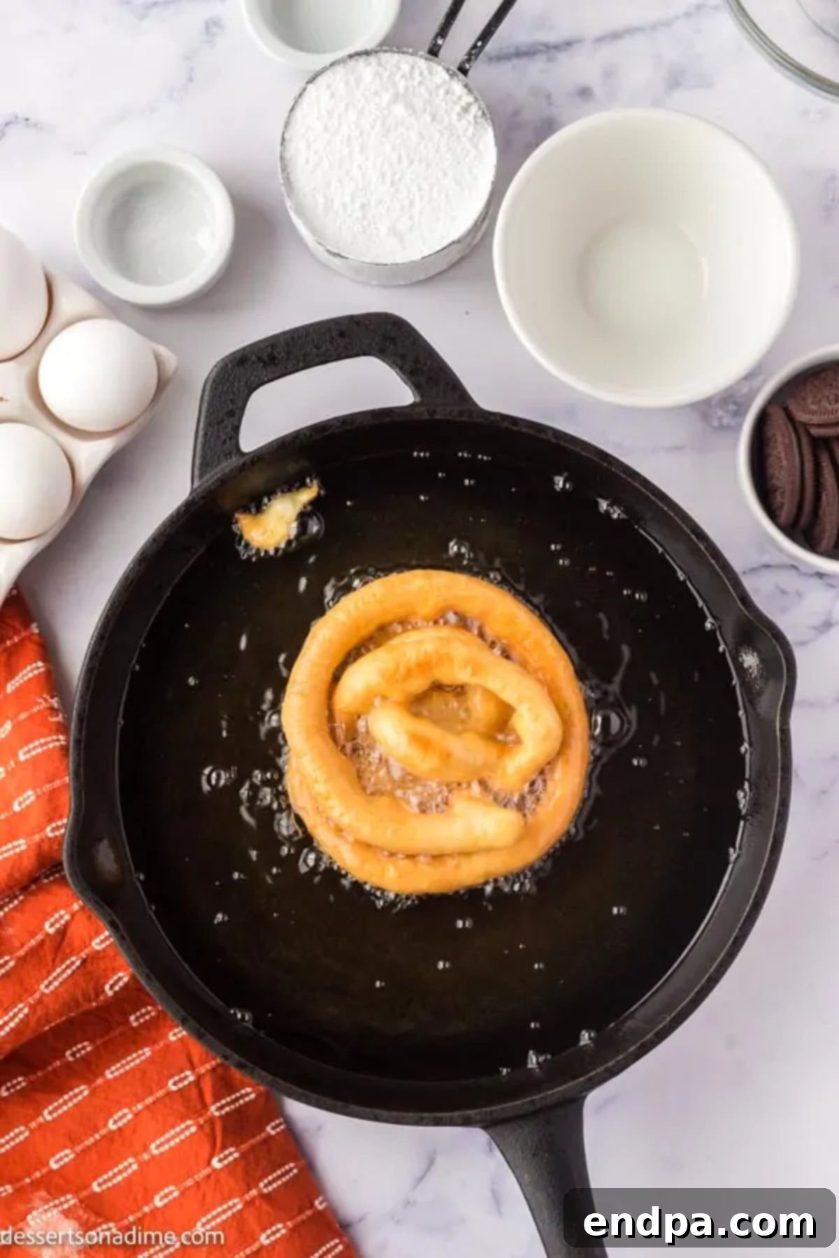 Funnel cake batter being fried in hot oil, forming its characteristic intricate design.