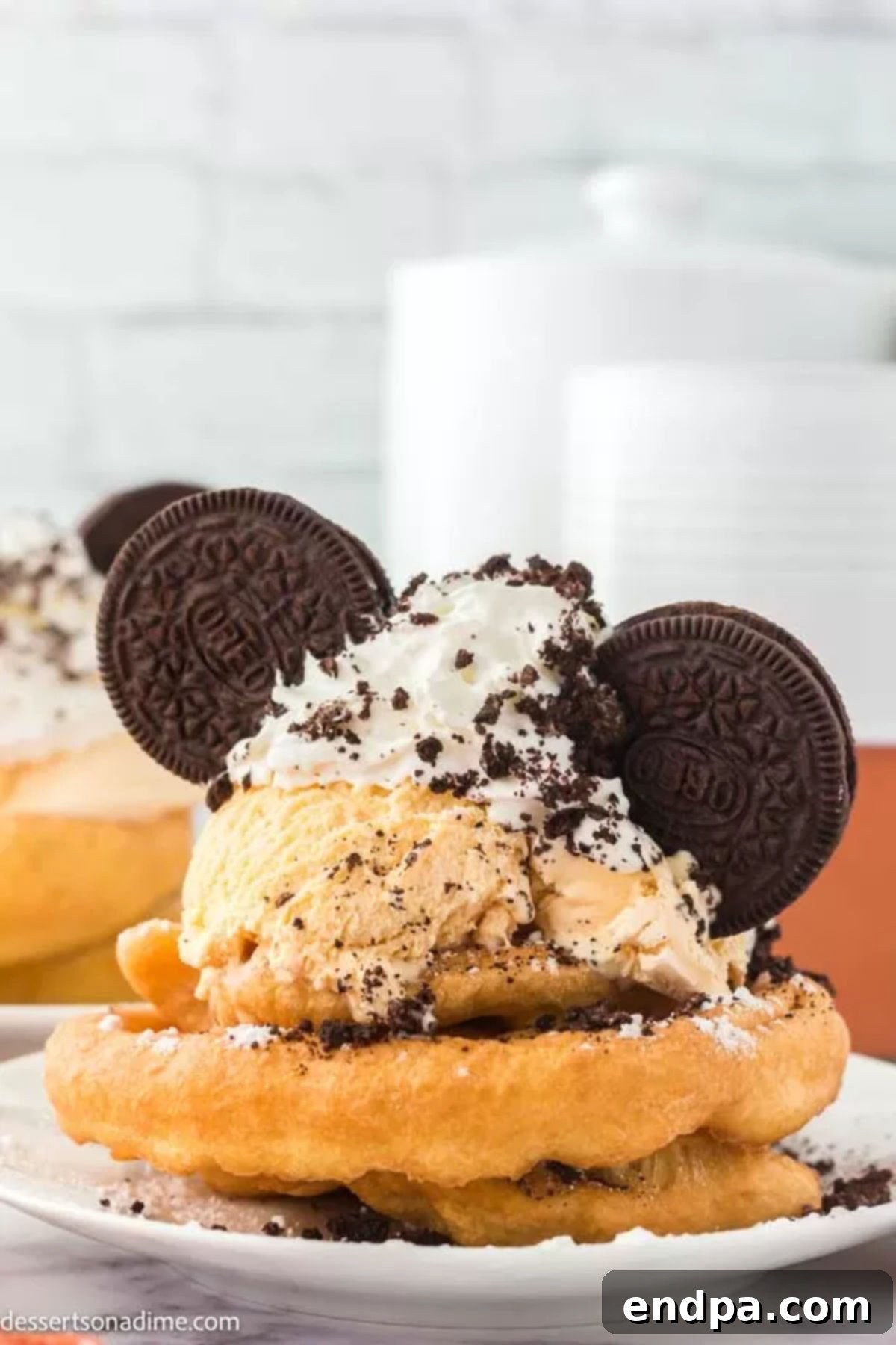 Freshly fried funnel cake topped generously with vanilla ice cream, whipped cream, crushed Oreos, and whole Oreo 'Mickey ears'.