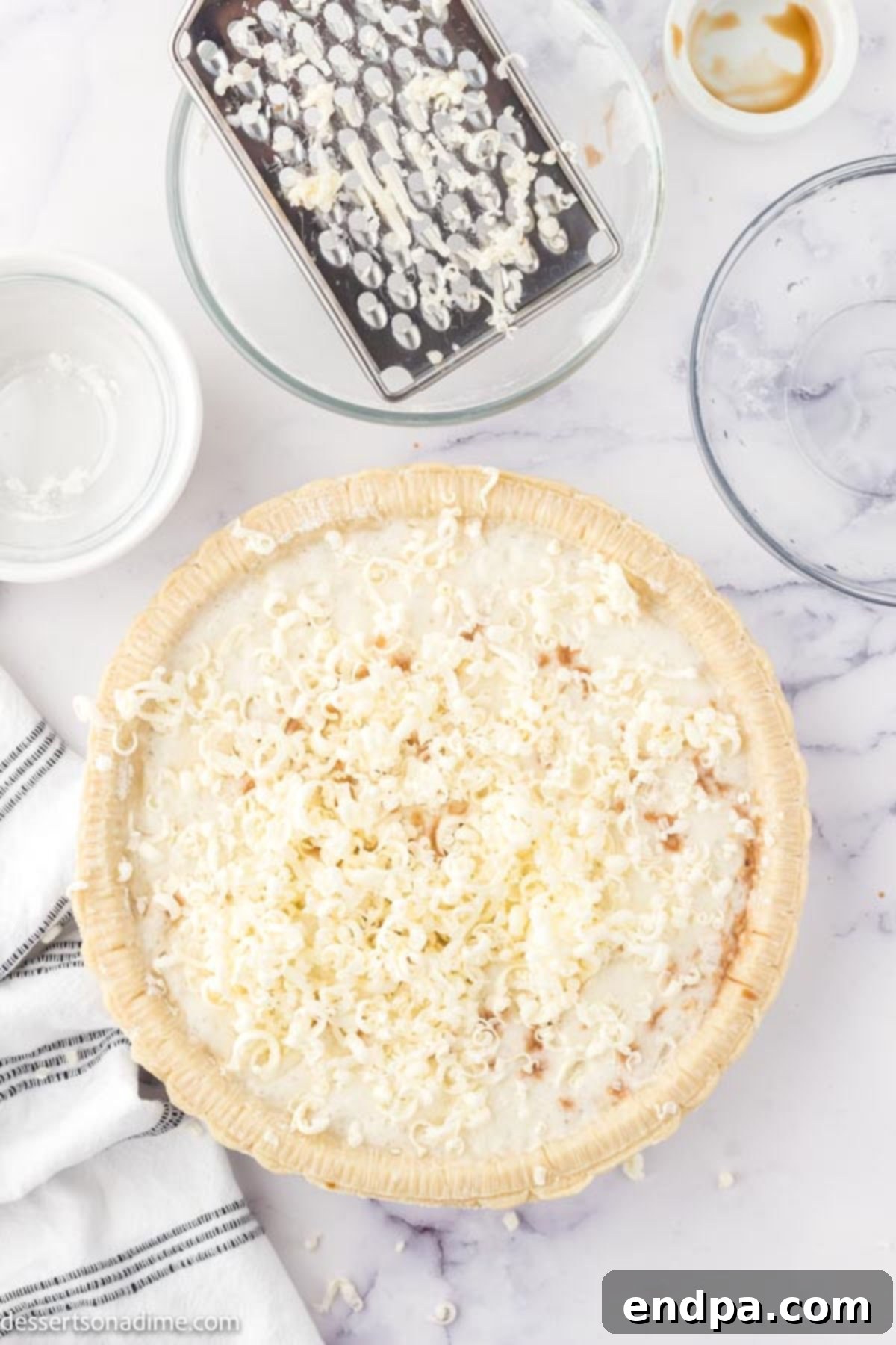 Grated butter being sprinkled on top of the pie filling mixture, ready for baking.