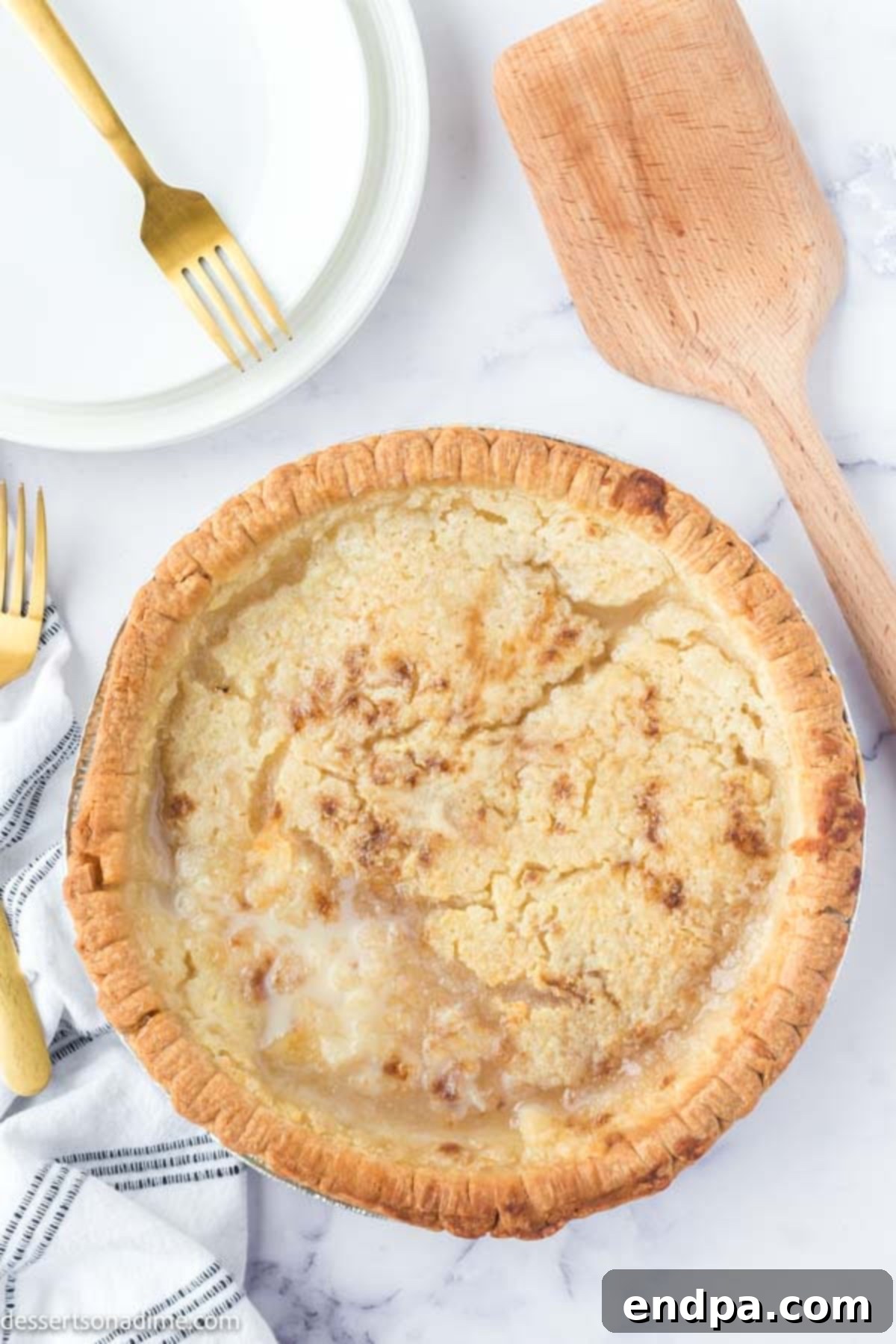 A pie covered with aluminum foil, with an 'X' cut in the center and the triangles peeled back to protect the crust from burning.