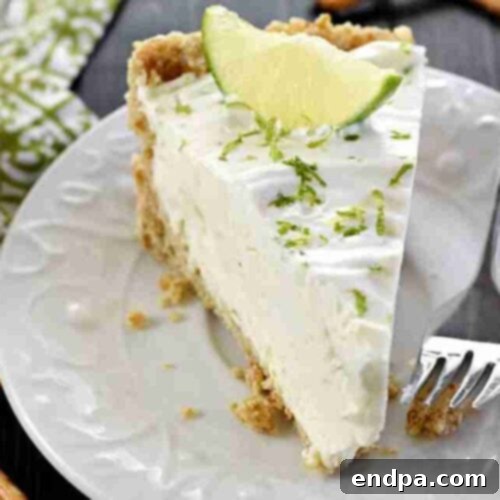 A slice of creamy No-Bake Frozen Margarita Pie, garnished with lime slices and a salty-sweet pretzel crust.